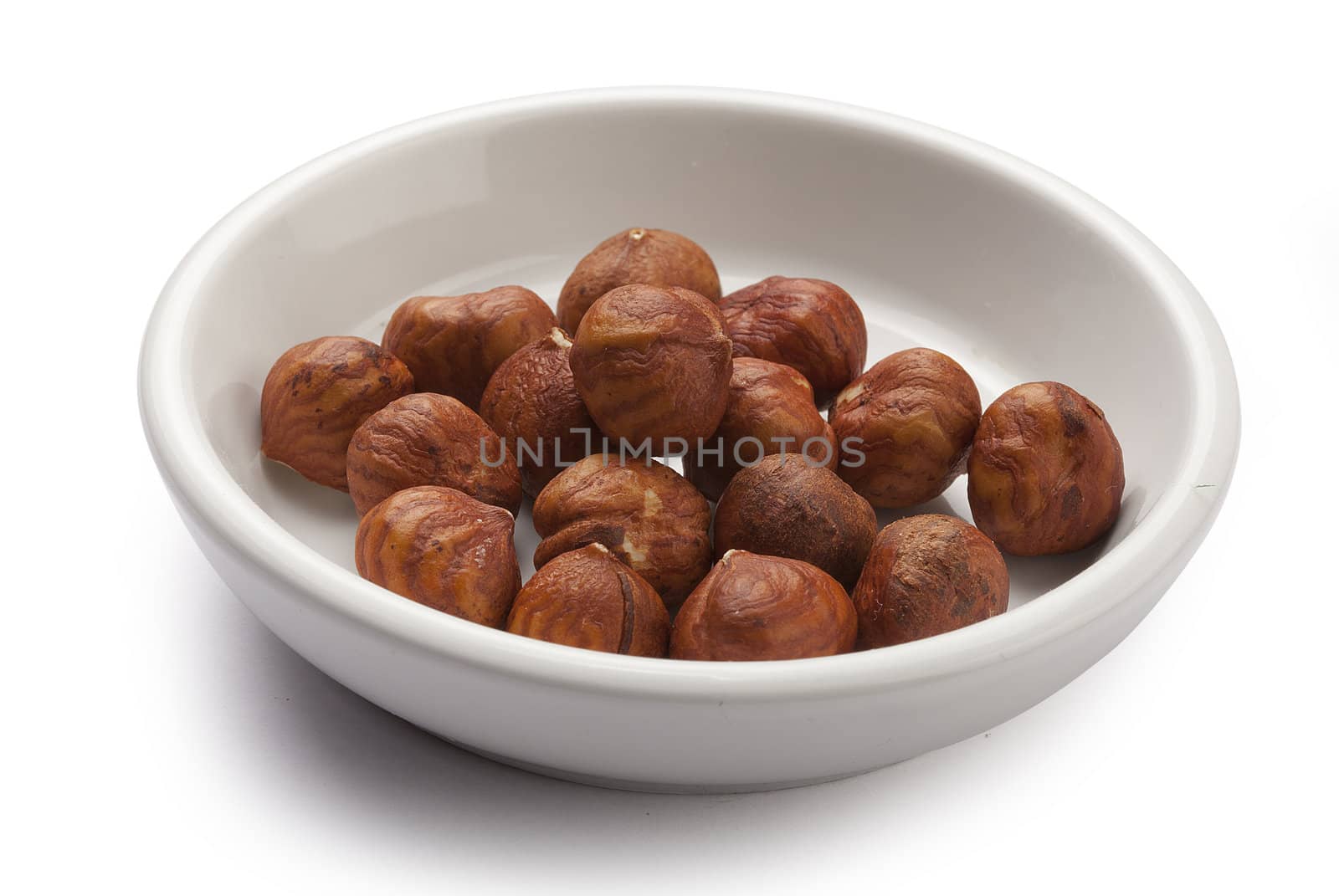 Handful of brown hazelnuts in the white plate