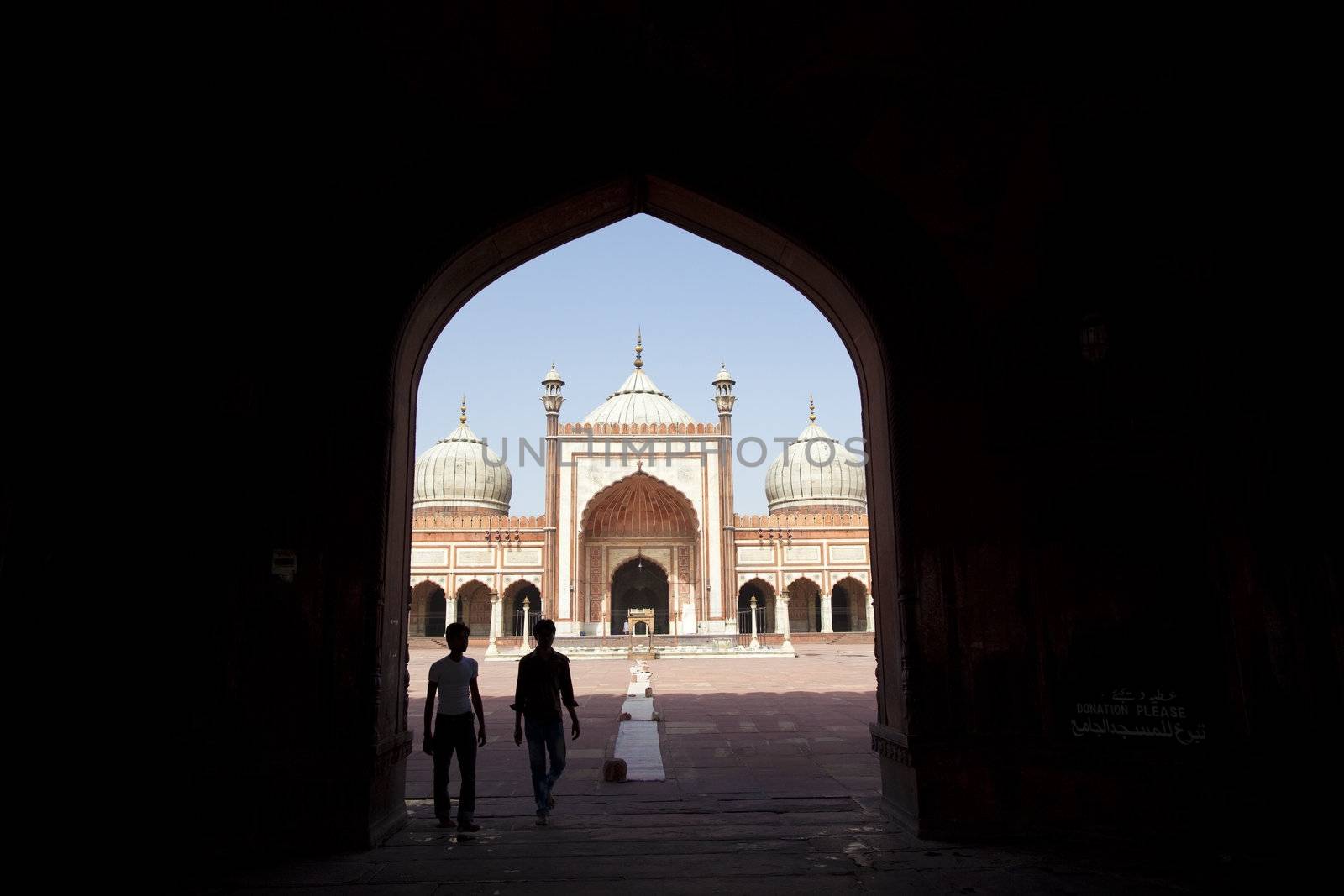 Jama Masjib mosque visitors walking through arch, Delhi, Punjab, India