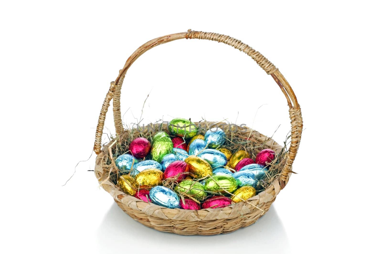 Little colored eggs in a basket with straw
