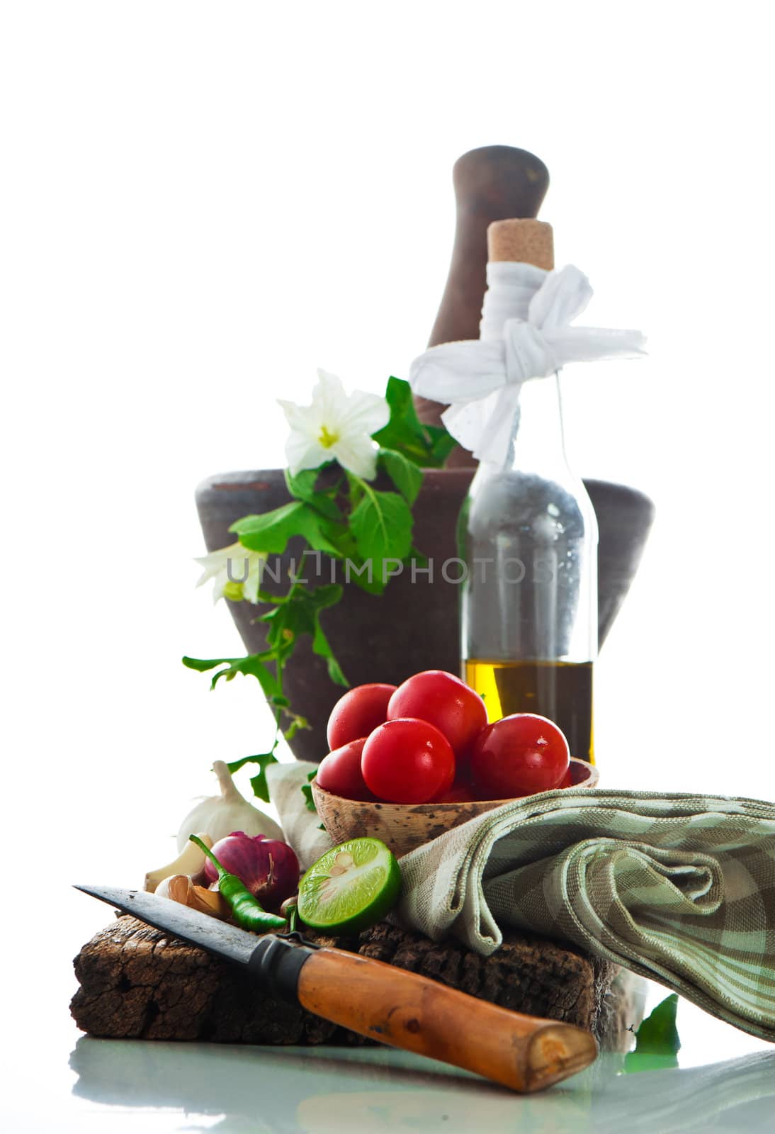 fresh vegetables and olive oil on an old weathered wood with a old mortar in behind over white background