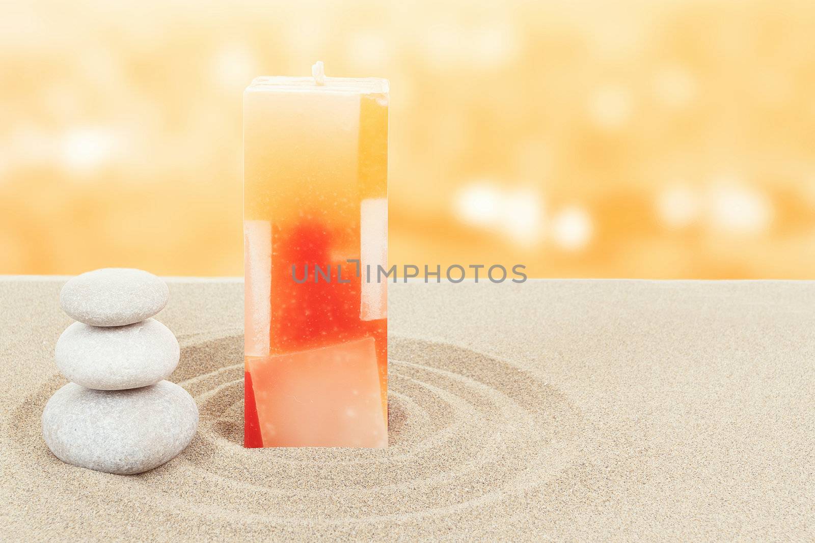 Balance zen stones and candle in sand on bokeh background