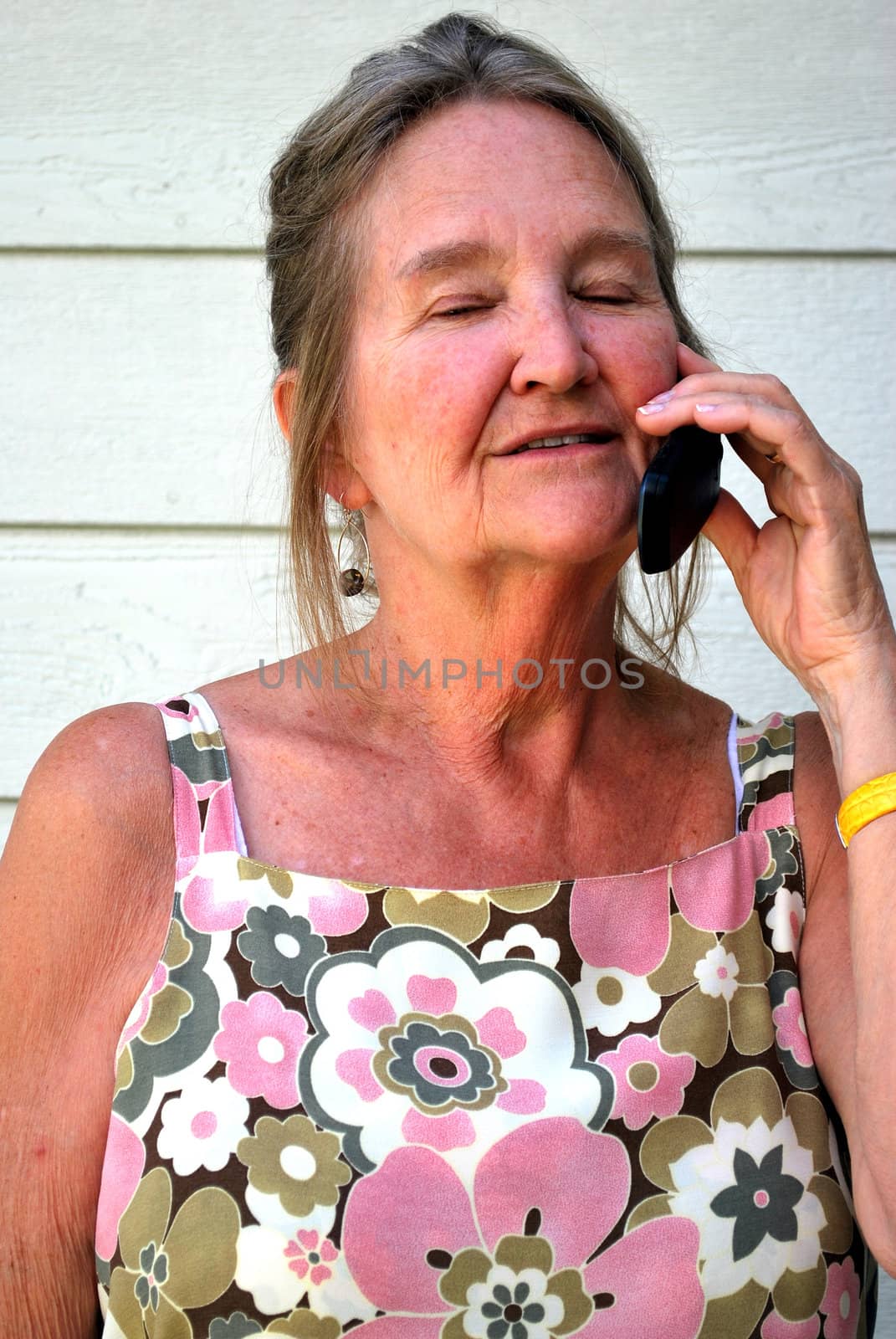 Mature female beauty talking on her cellphone outside.