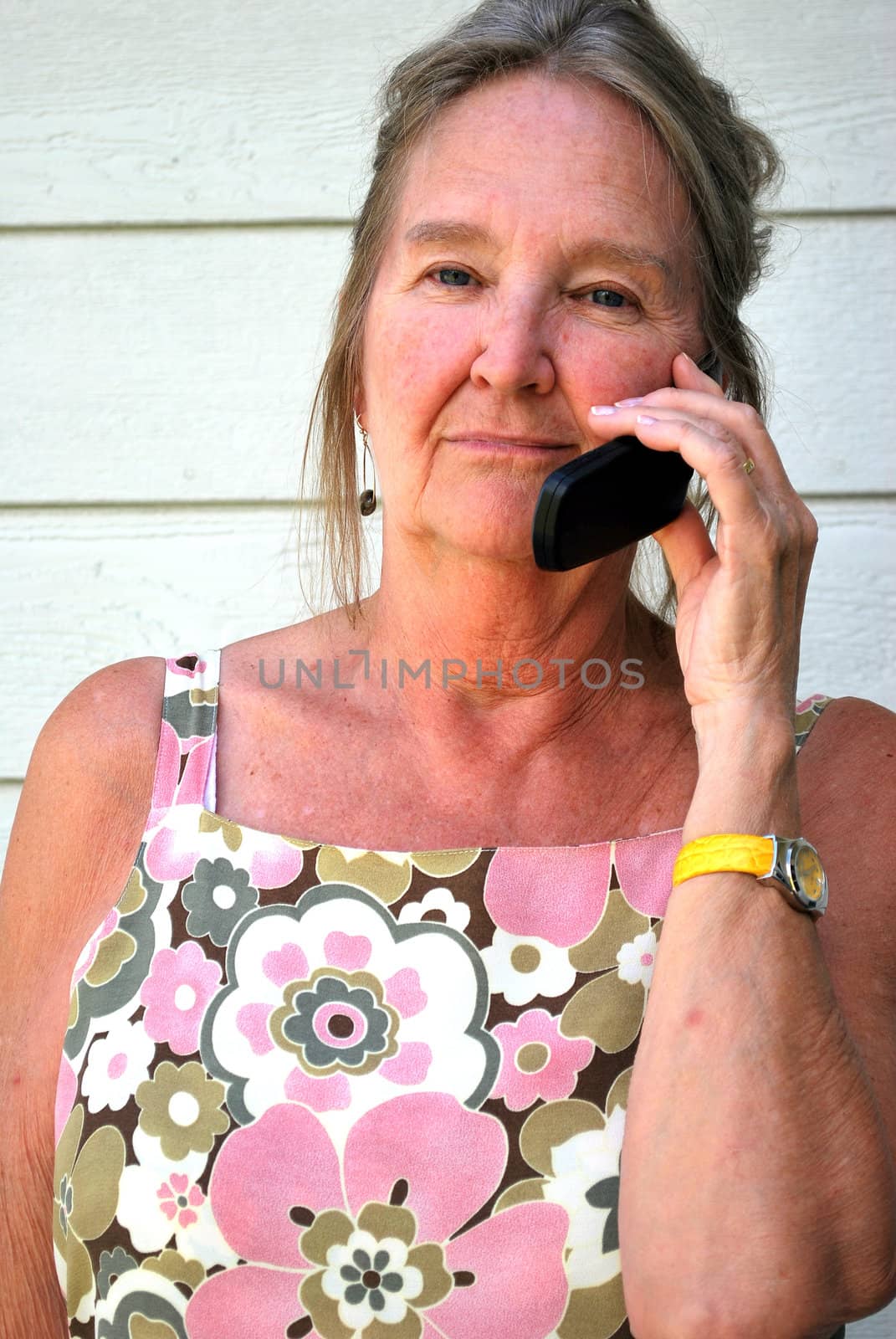 Mature female beauty talking on her cellphone outside.