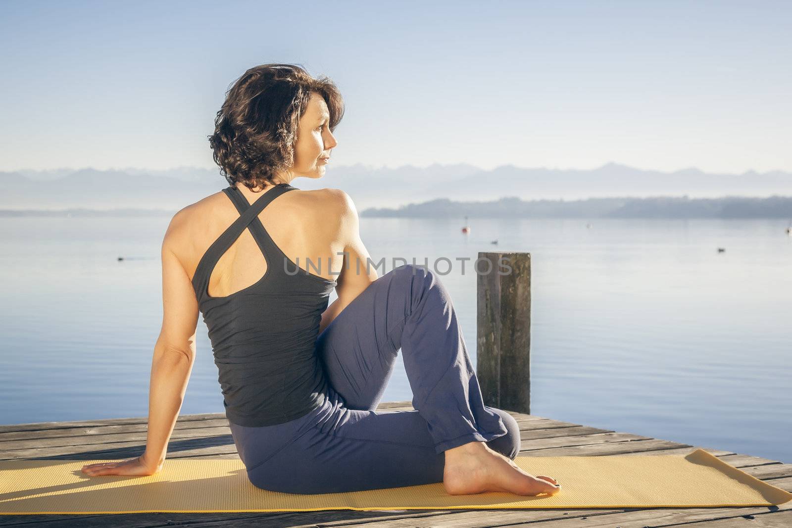 An image of a pretty woman doing yoga at the lake - Ardha Matsyendrasana