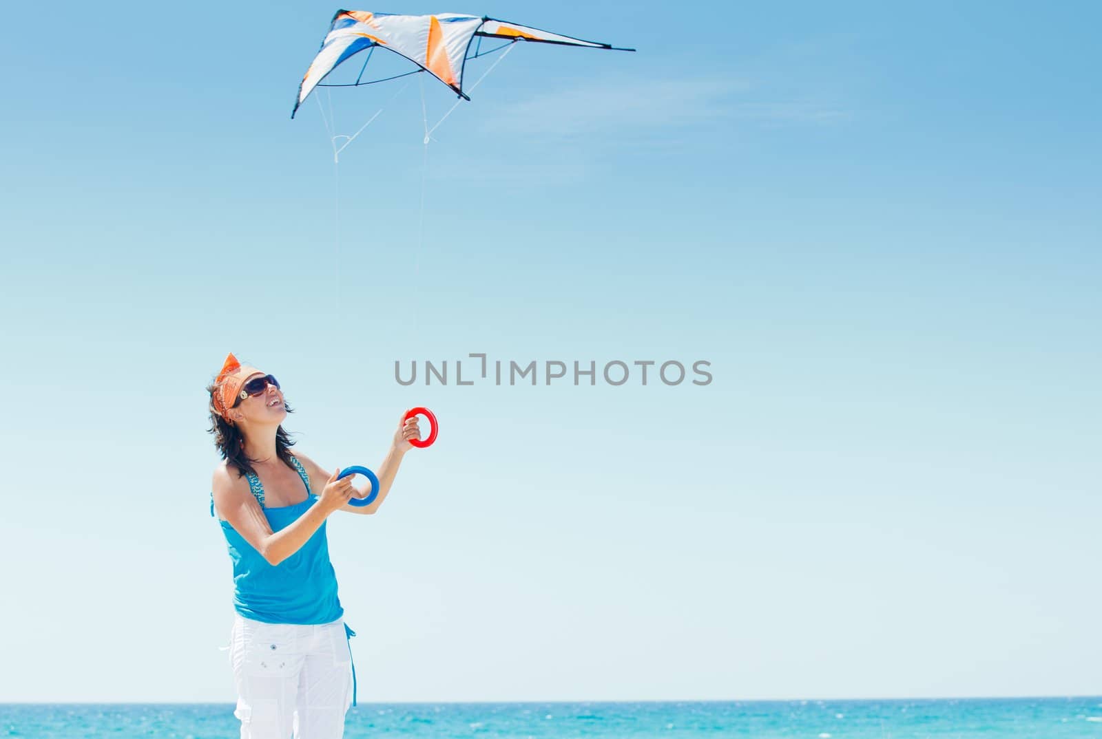 Young cute woman playing with a colorful kite on the tropical beach.