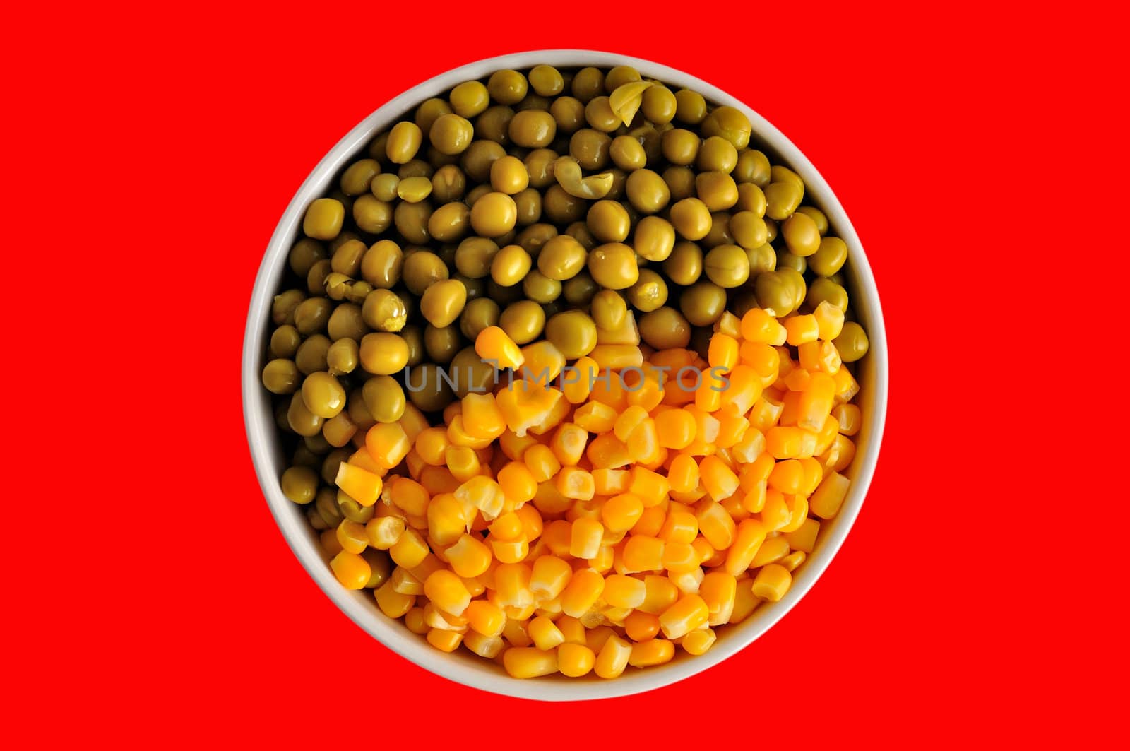 a plate with corn and peas, isolated, on a red background