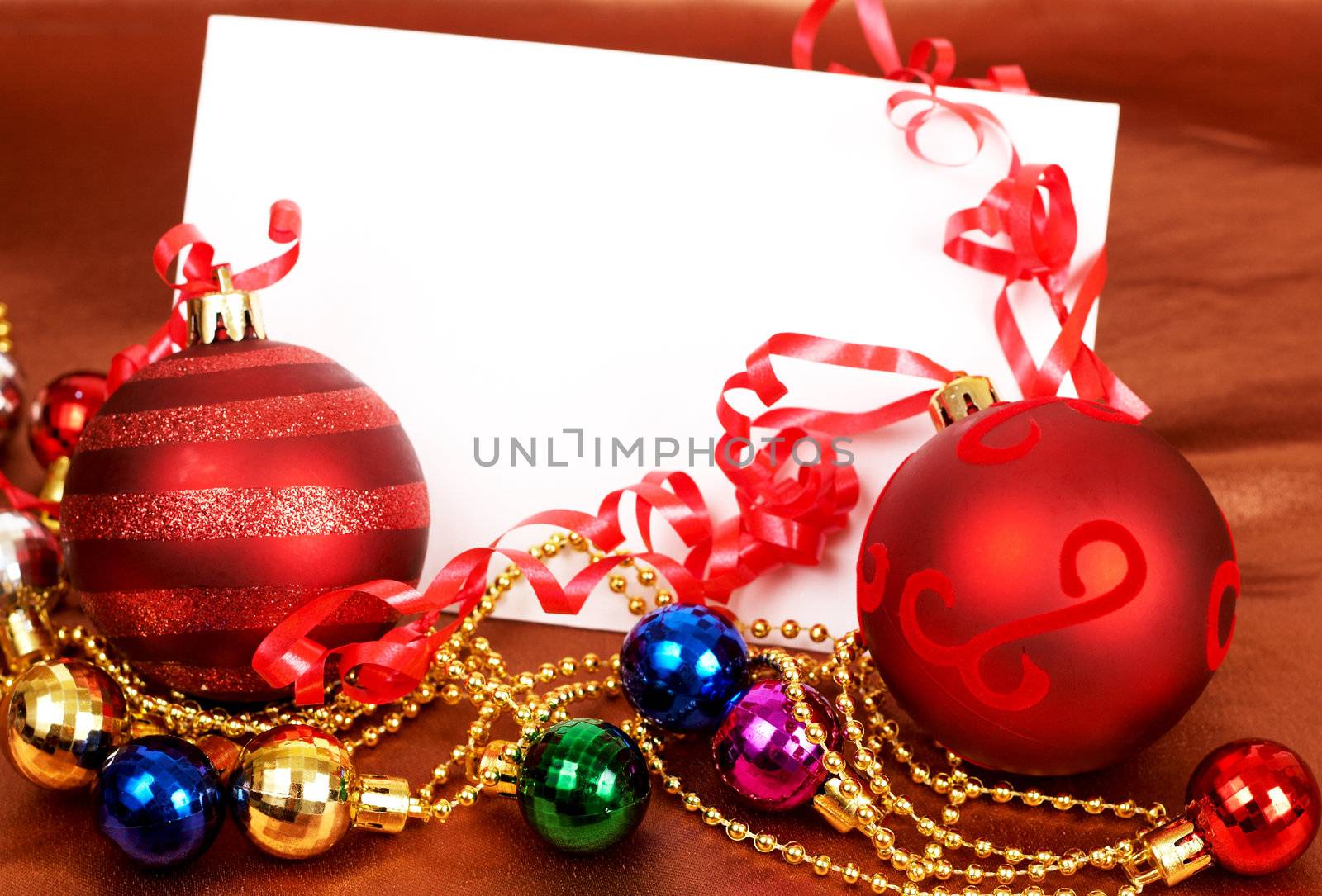 Red and other colorful Christmas baubles and white card with copy space. 