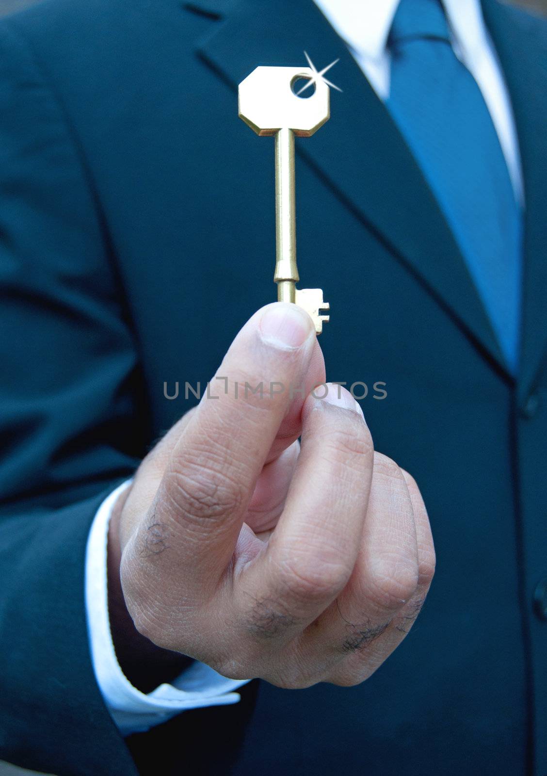 Businessman holding a shiny gold key