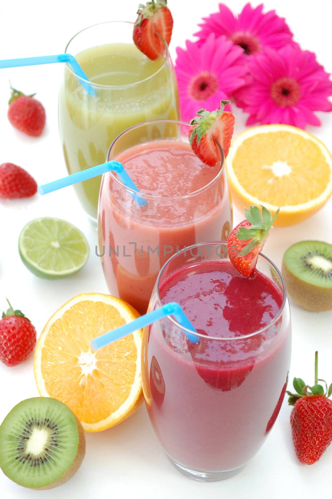 Various smoothies surrounded by fruit and flowers 