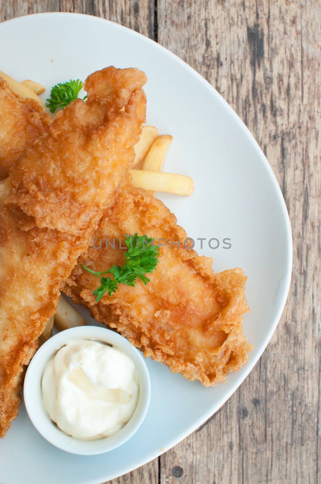Two battered fish fillets on a plate with chips and mayonnaise