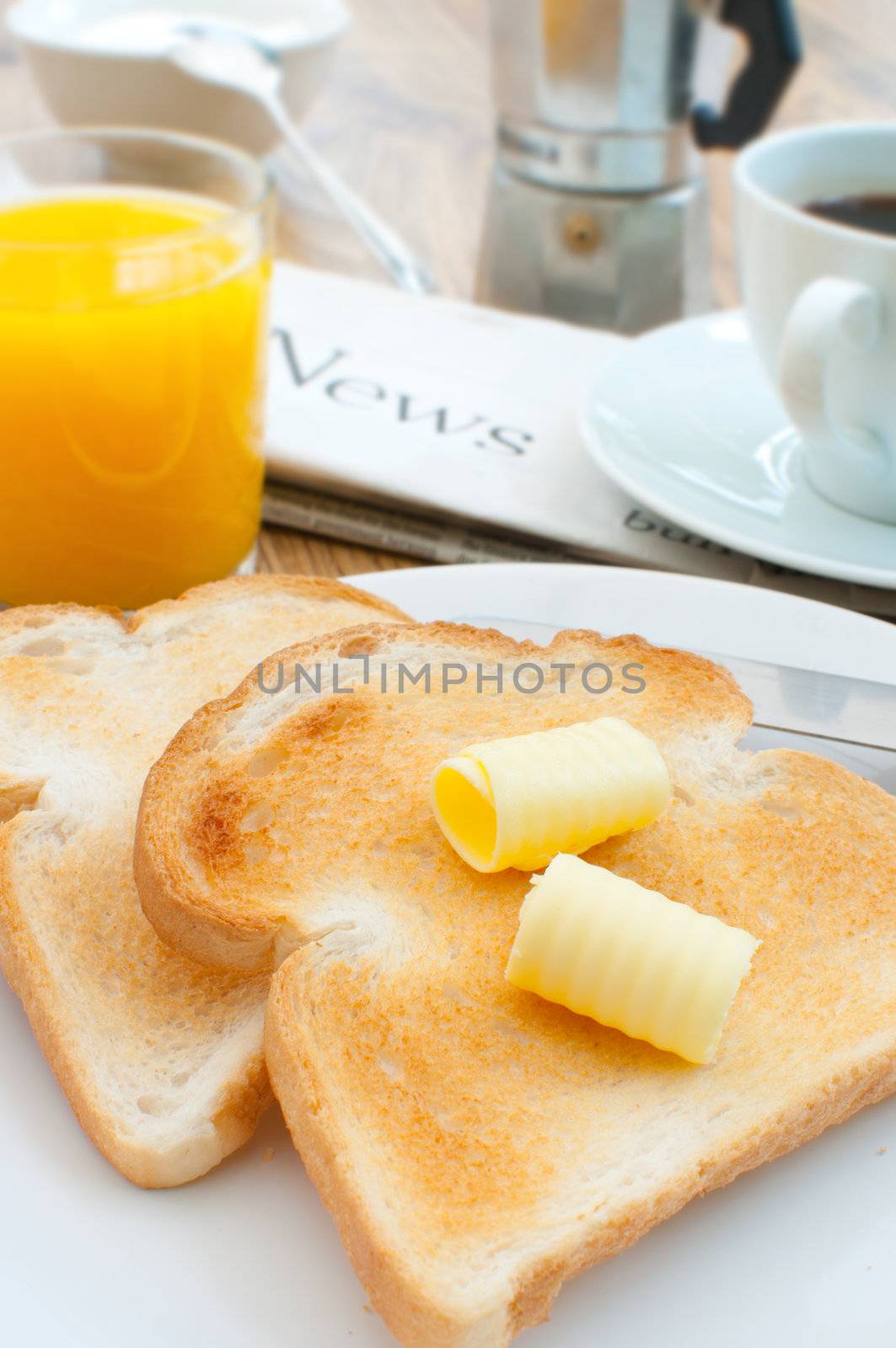 Butter on toast with coffee and newspaper in the background