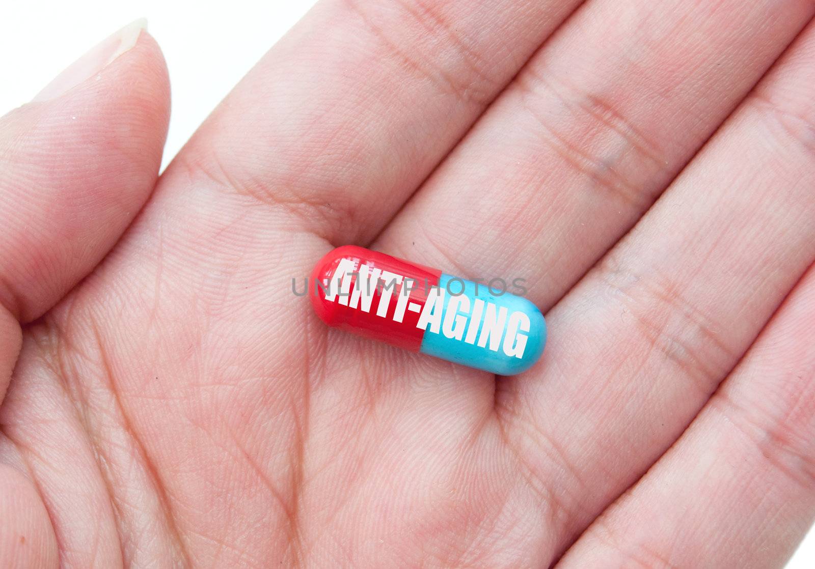 Hand holding a pill labelled with anti-aging