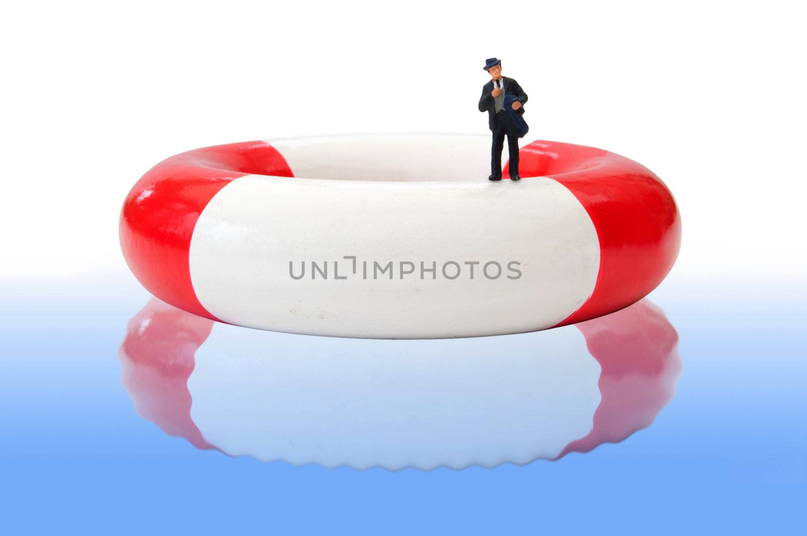 Miniature businessman floating on a life ring