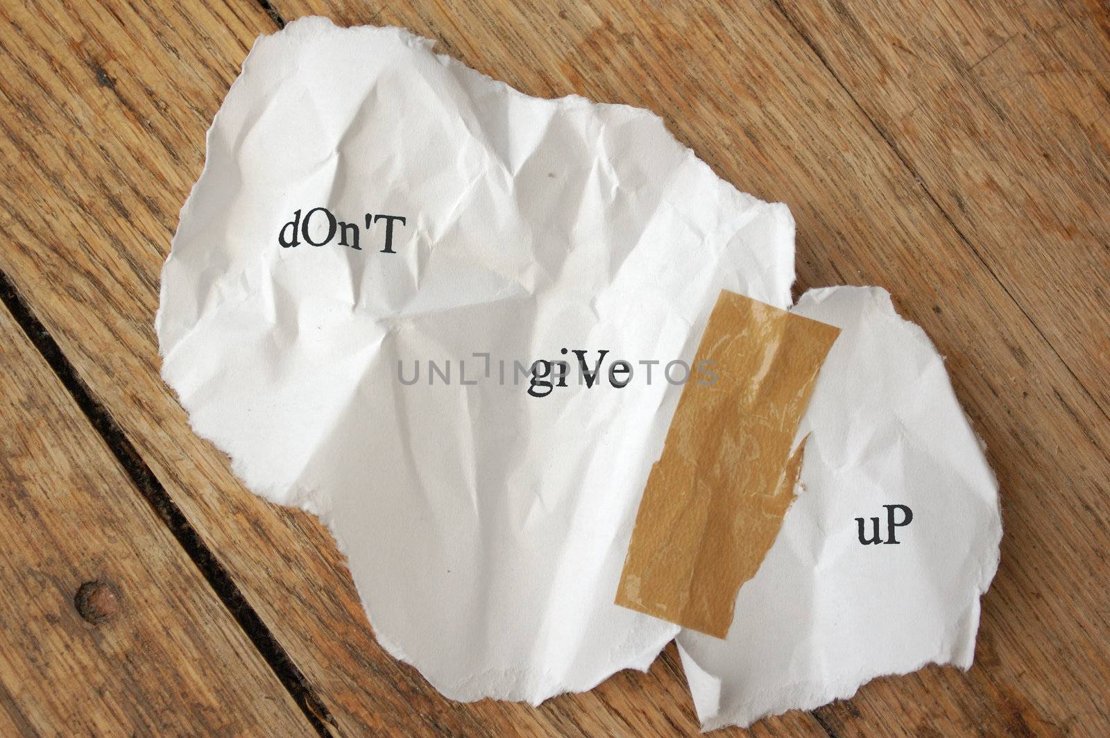 Crumpled piece of torn paper stuck together with tape with the message dont give up