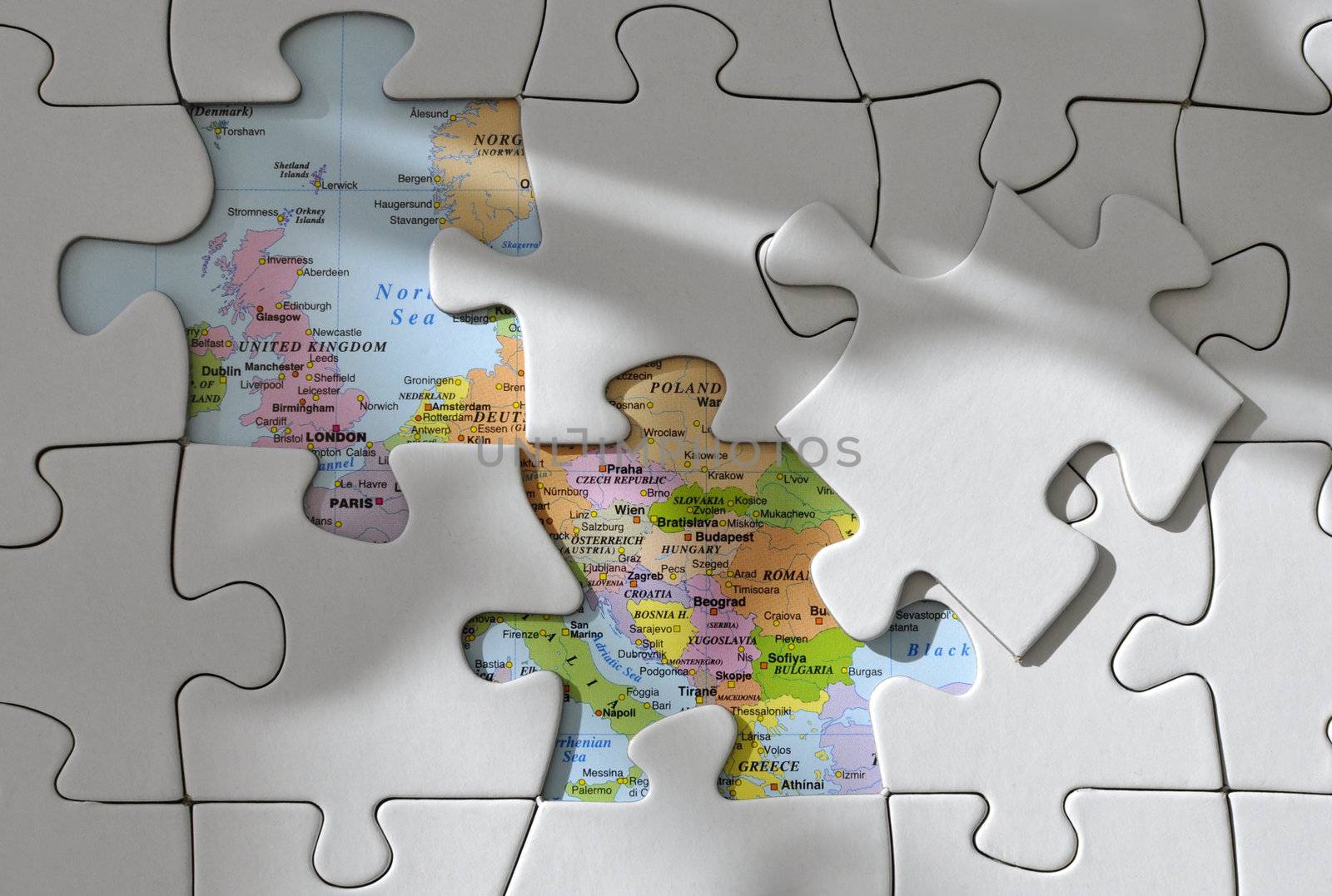 Missing pieces from a jigsaw puzzle with a map of Europe underneath