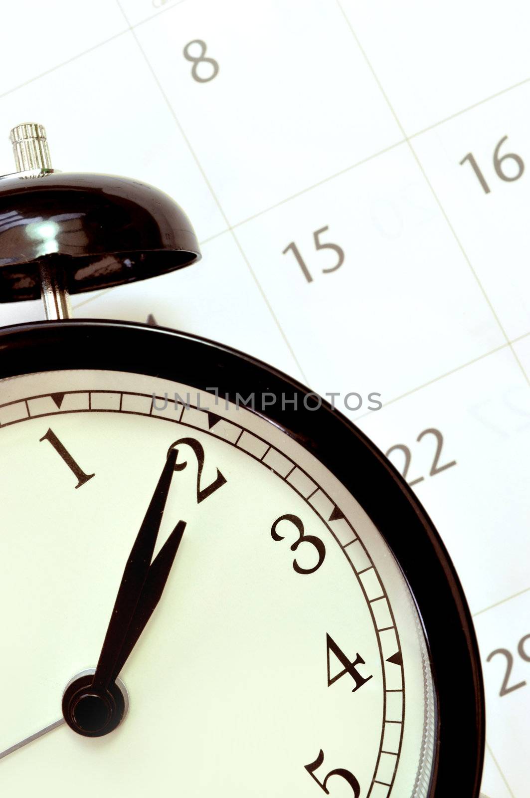 Closeup of an alarm clock on top of a calendar 