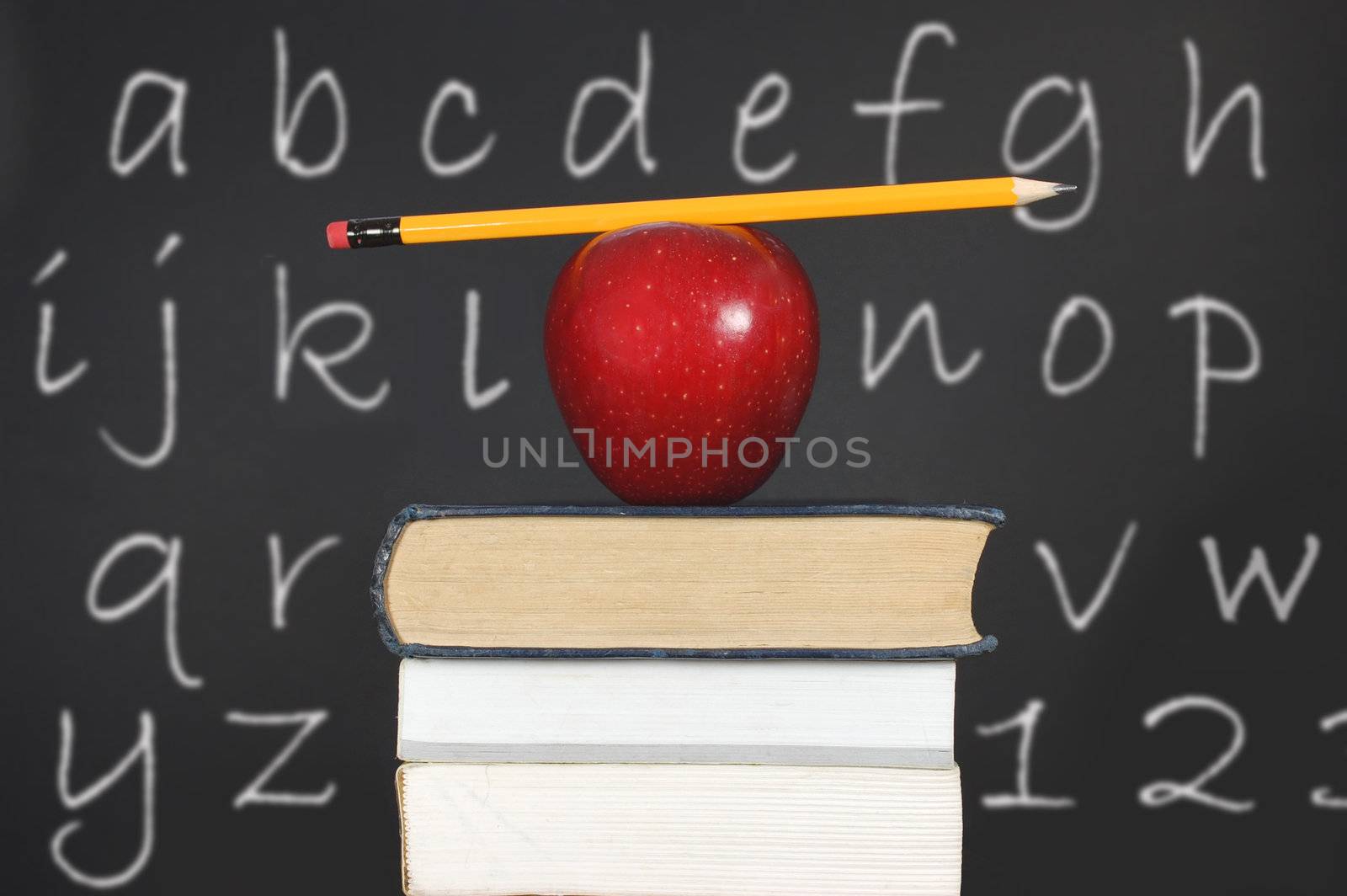 Pencil balancing on an apple and a stack of books