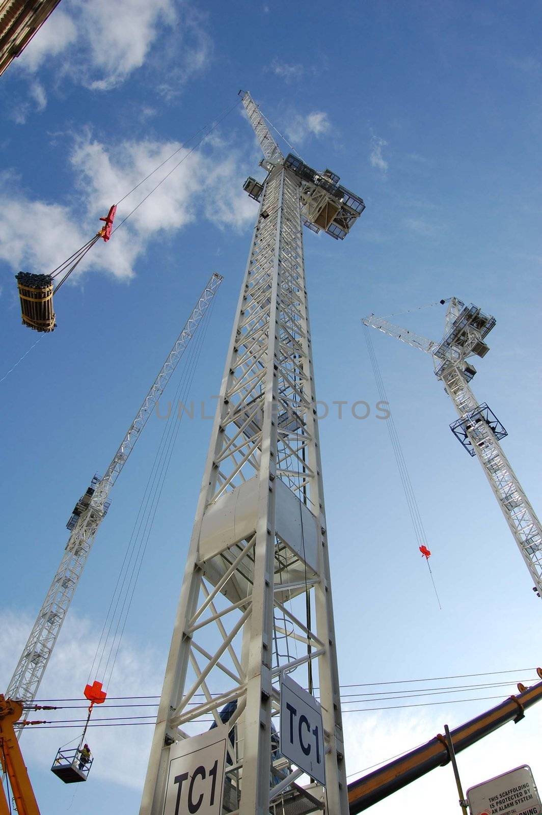 Tall construction cranes against a blue sky