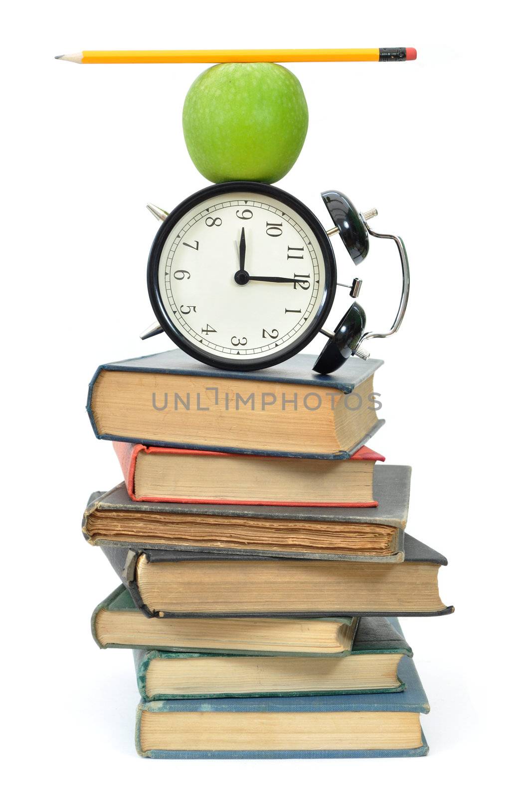 Balancing act of objects, including an apple and closk, on top of a stack of books 