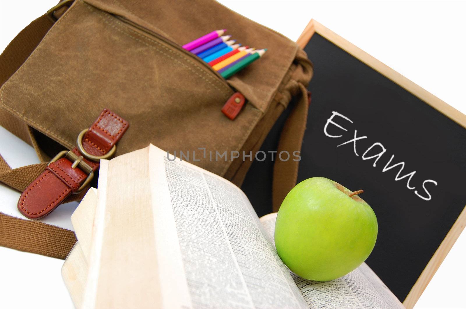 Satchel and books next to a blackboard with the word exams