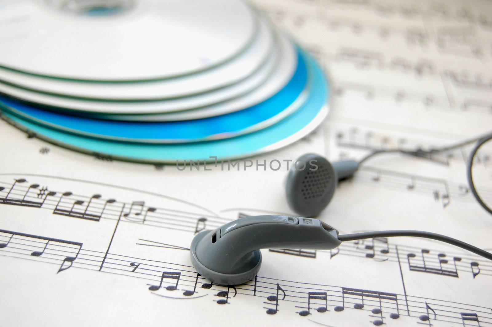 Pair of earphones on a music score with cds