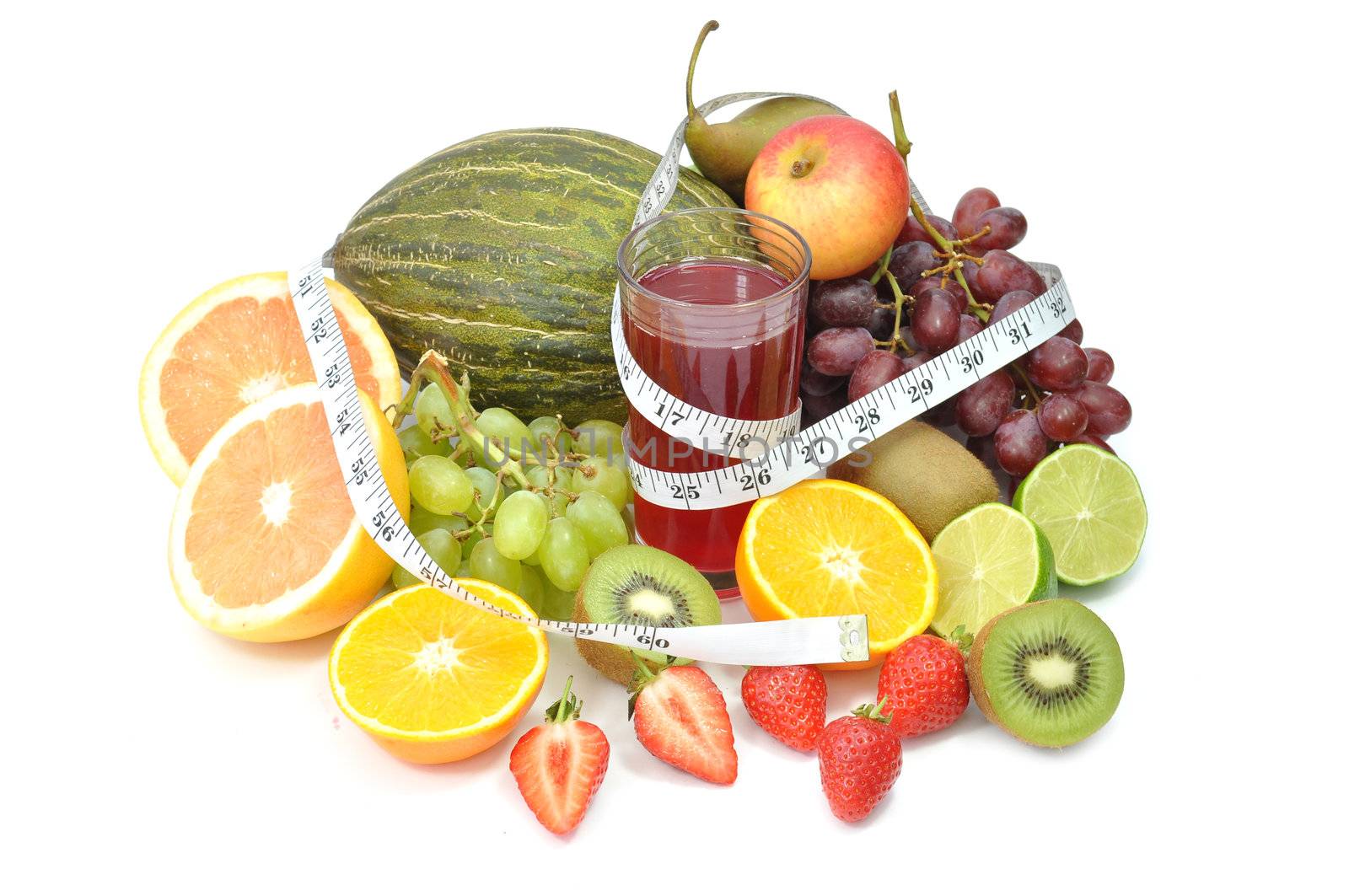 Fresh glass of juice surrounded by an assortment of fruit and a tape measure