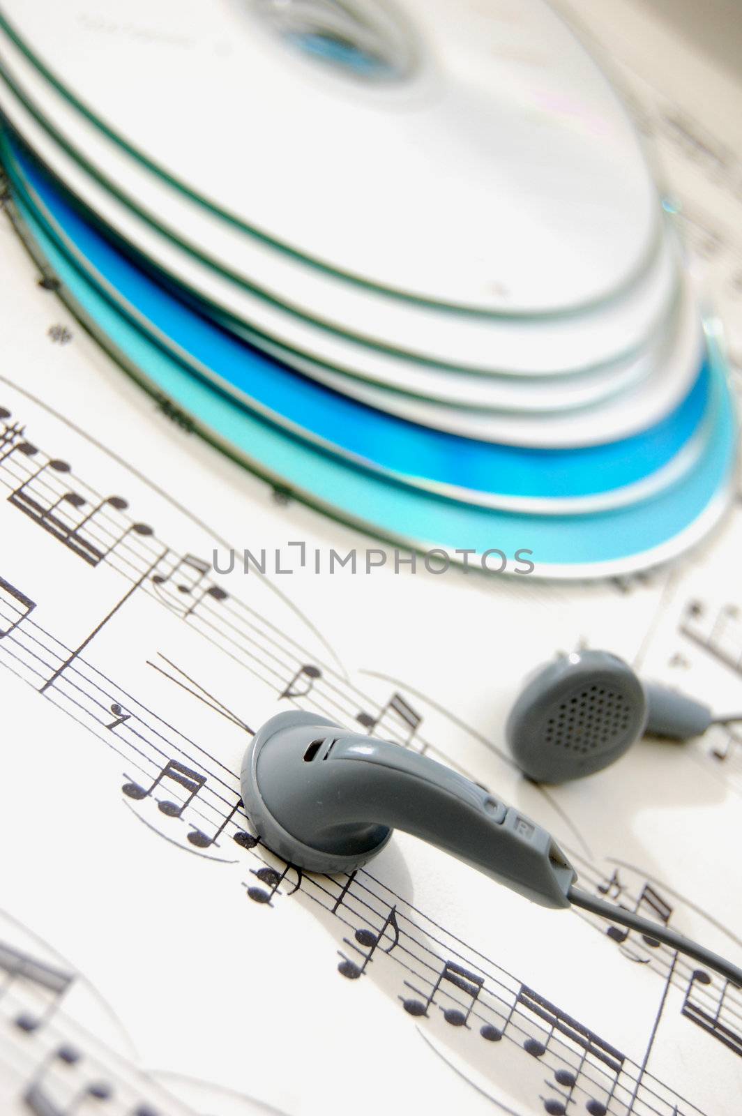 A pair of headphones on a music score with cds