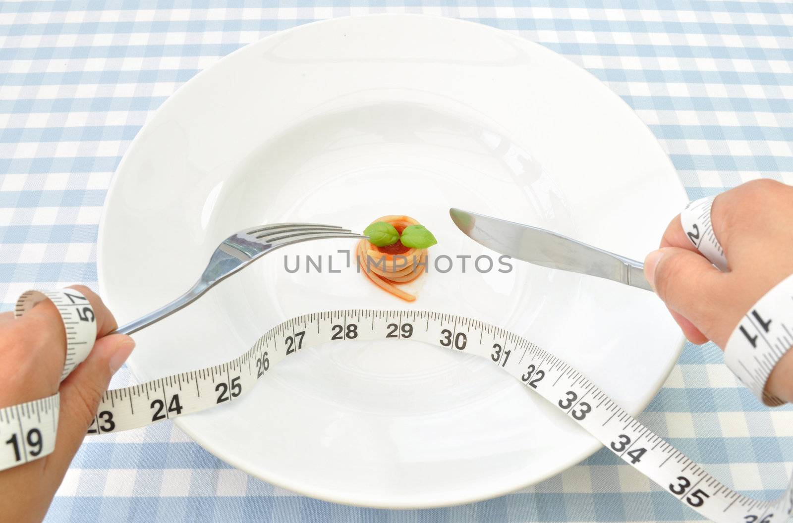 Small portion of spaghetti with basil and a measuring tape