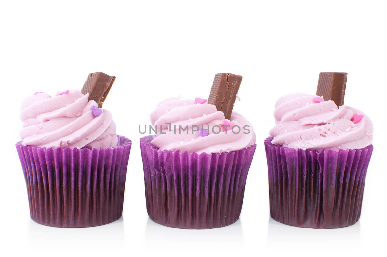 Delicious pink cupcakes with chocolate sticks on a white background