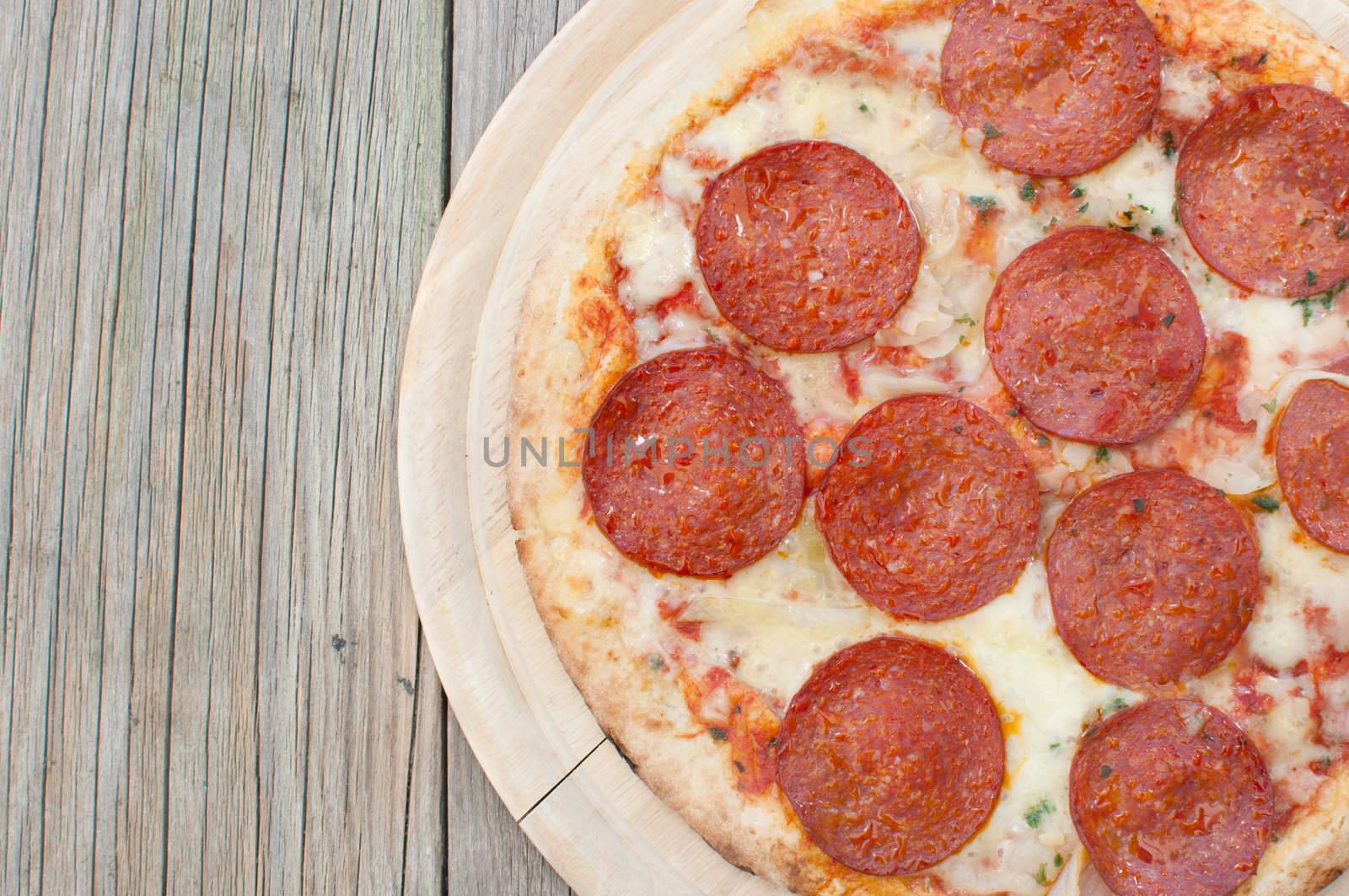 Closeup of a freshly cooked pepperoni pizza on a wooden board
