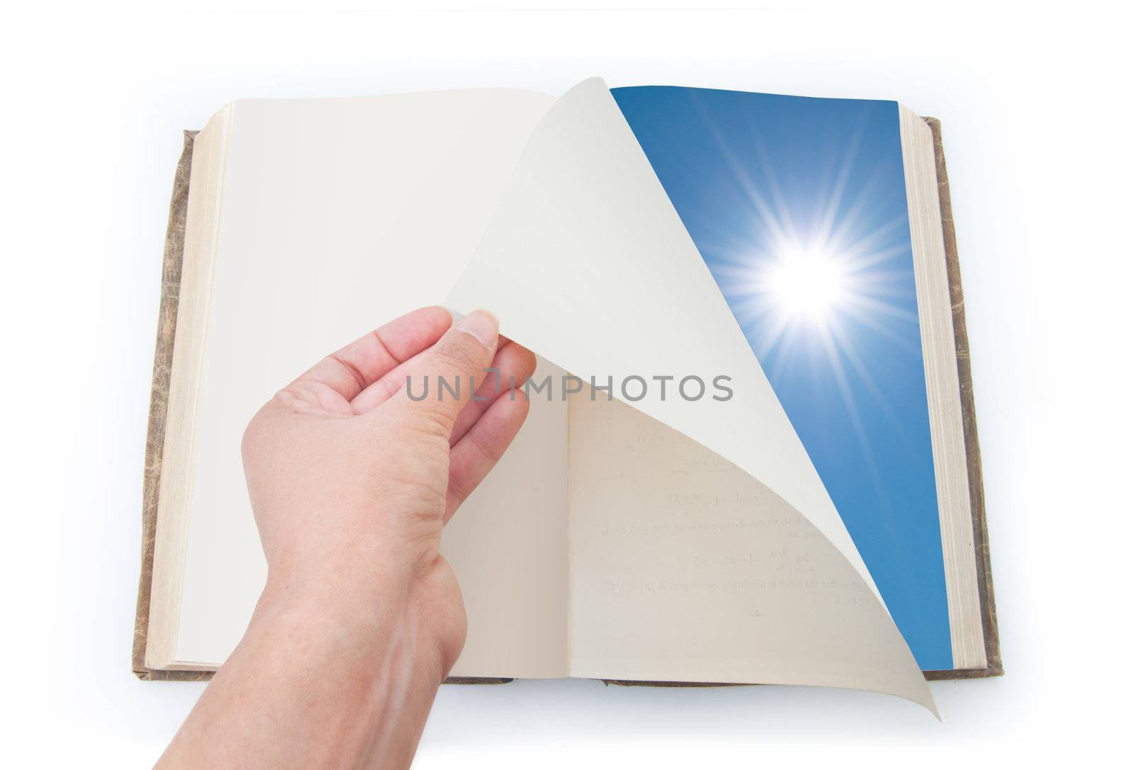Hand turning over the page of a book the image of blue sky and sun on the other side