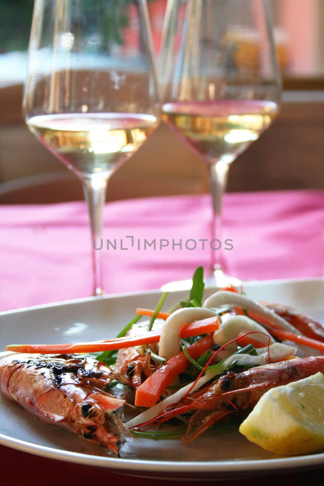 Italy. Liguria. Cinque Terre. Royal shrimps fried on a grill with vegetables and two bocals of white wine 