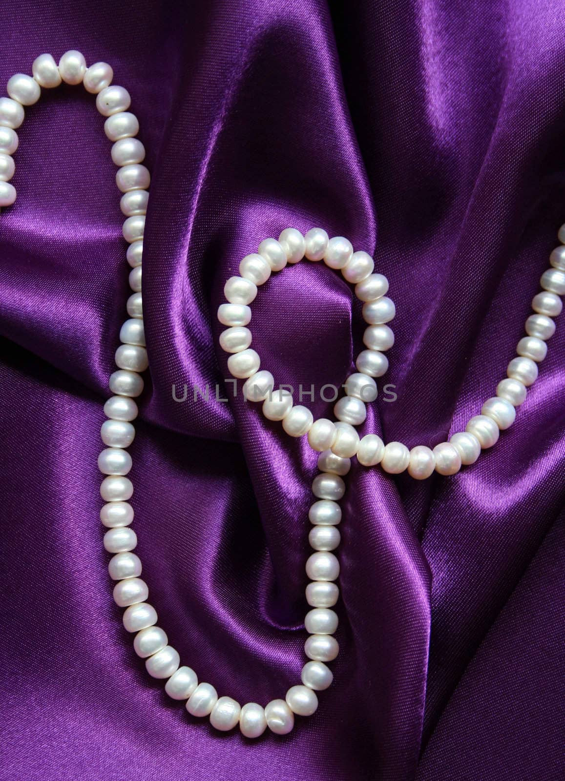 White pearls on a lilac silk as background 