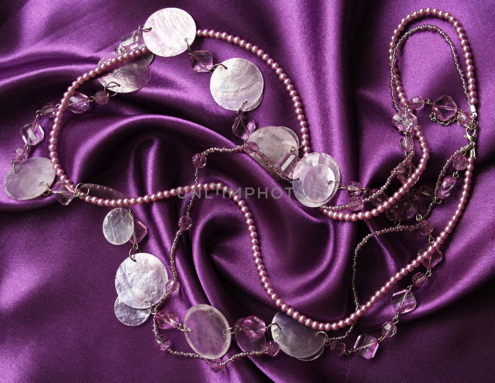 Lilac pearls and nacreous beeds on a lilac silk as background 