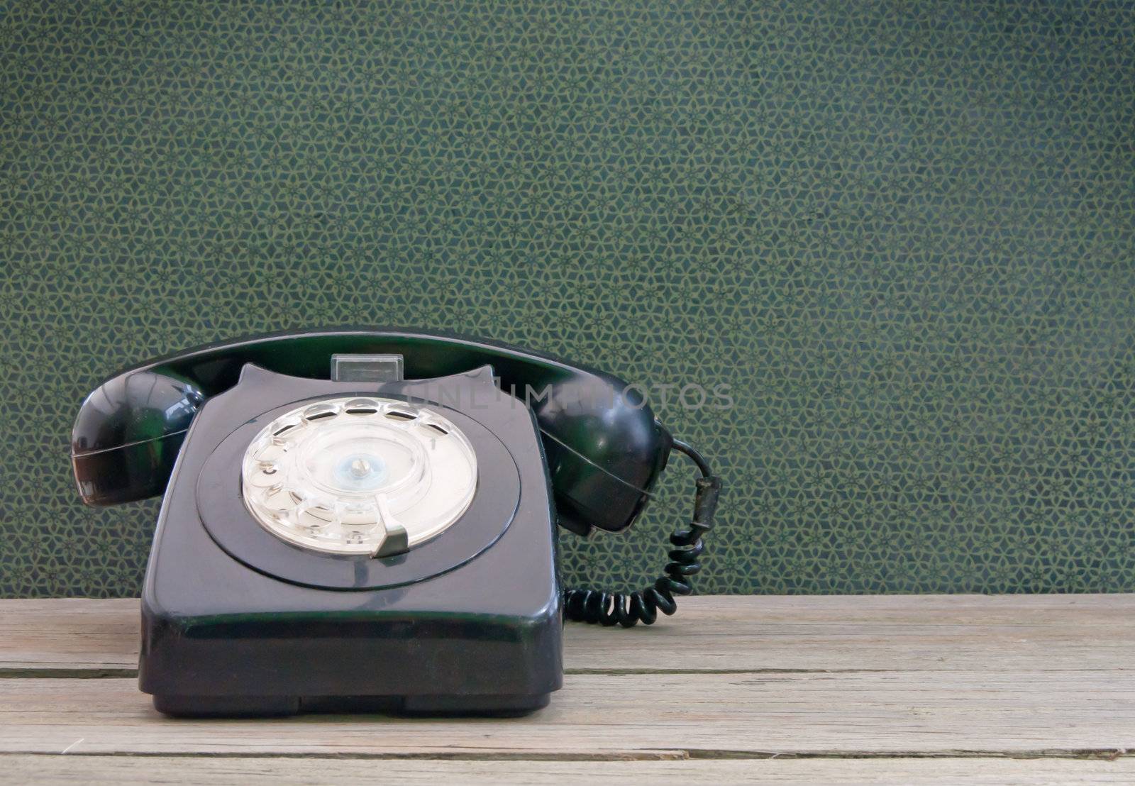 Vintage phone on a wooden table with wallpaper in the background