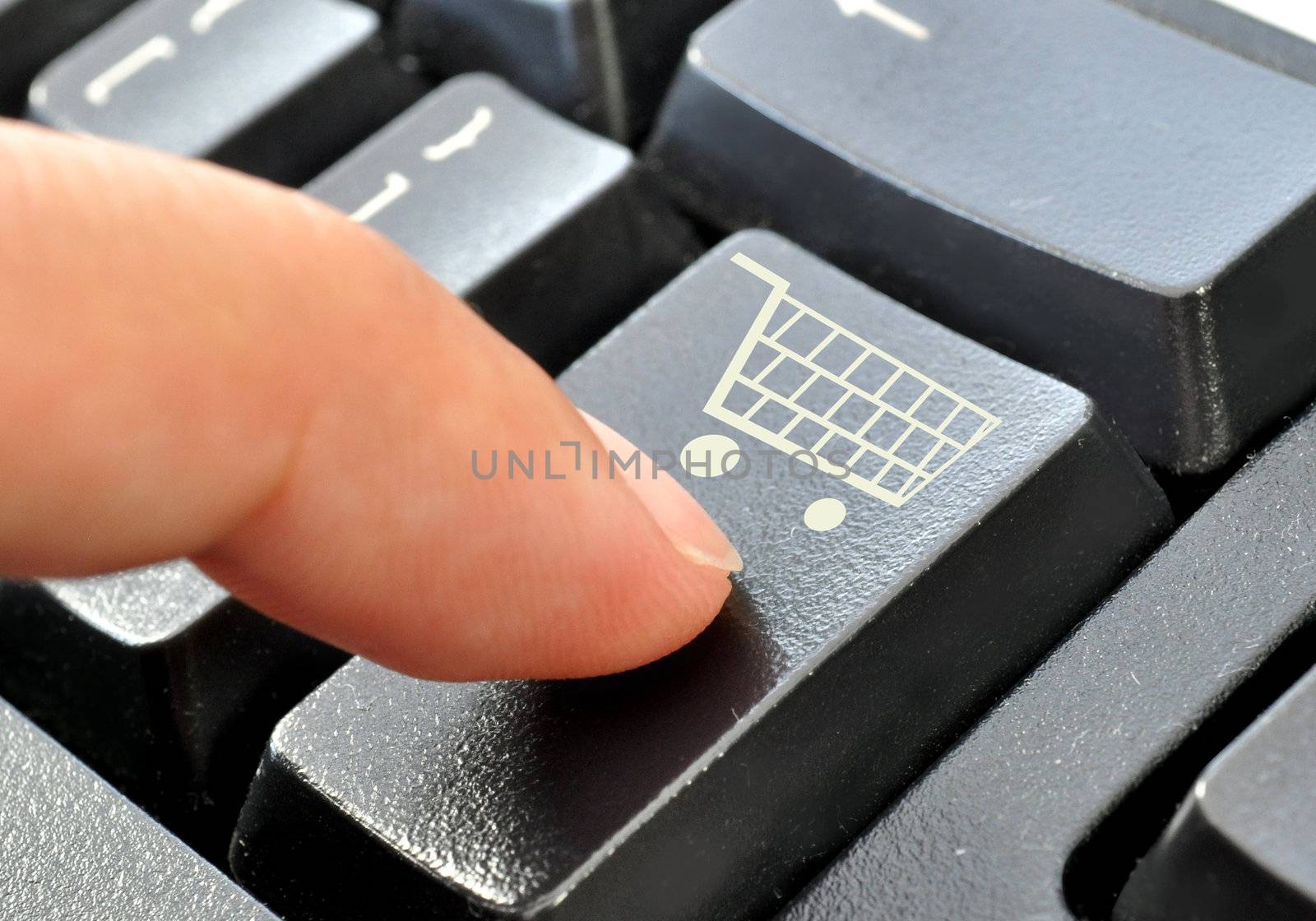 Finger pressing down on an enter key with a shopping cart icon 
