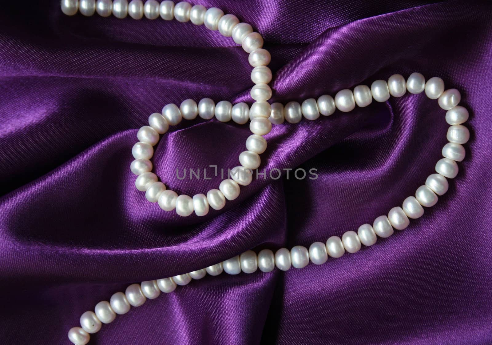 White pearls on a lilac silk as background 