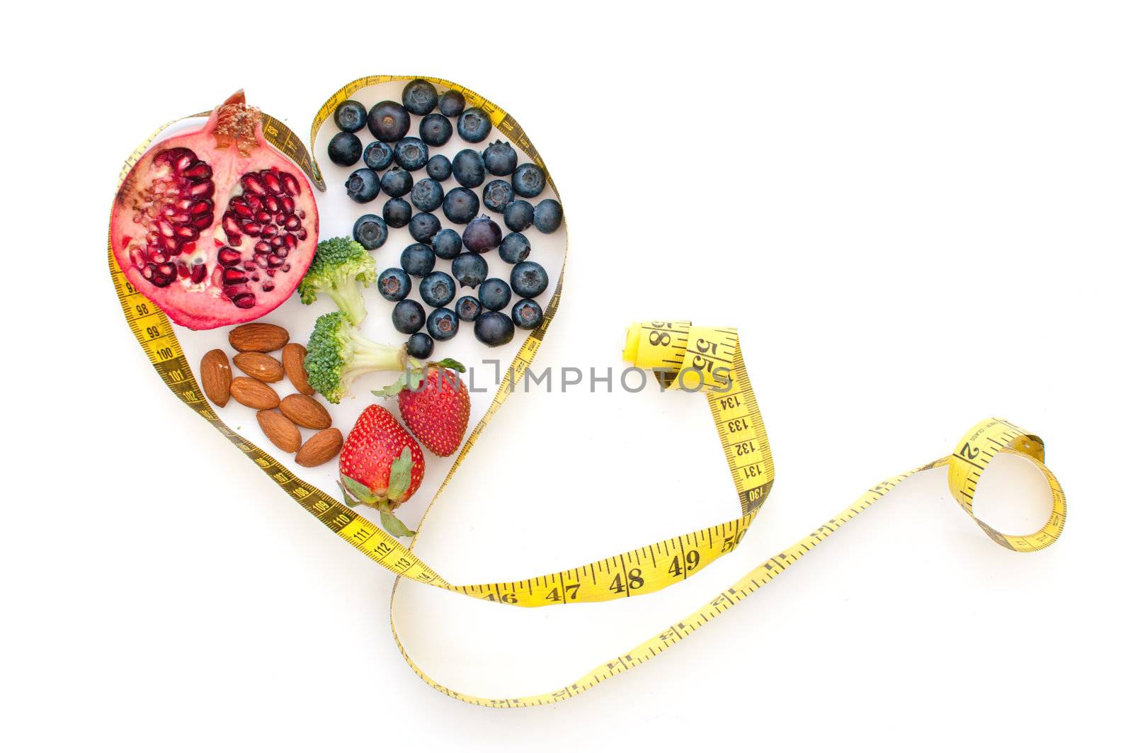 Superfoods such as pomegranate, blueberries and almonds inside a tape measure in the shape of a heart