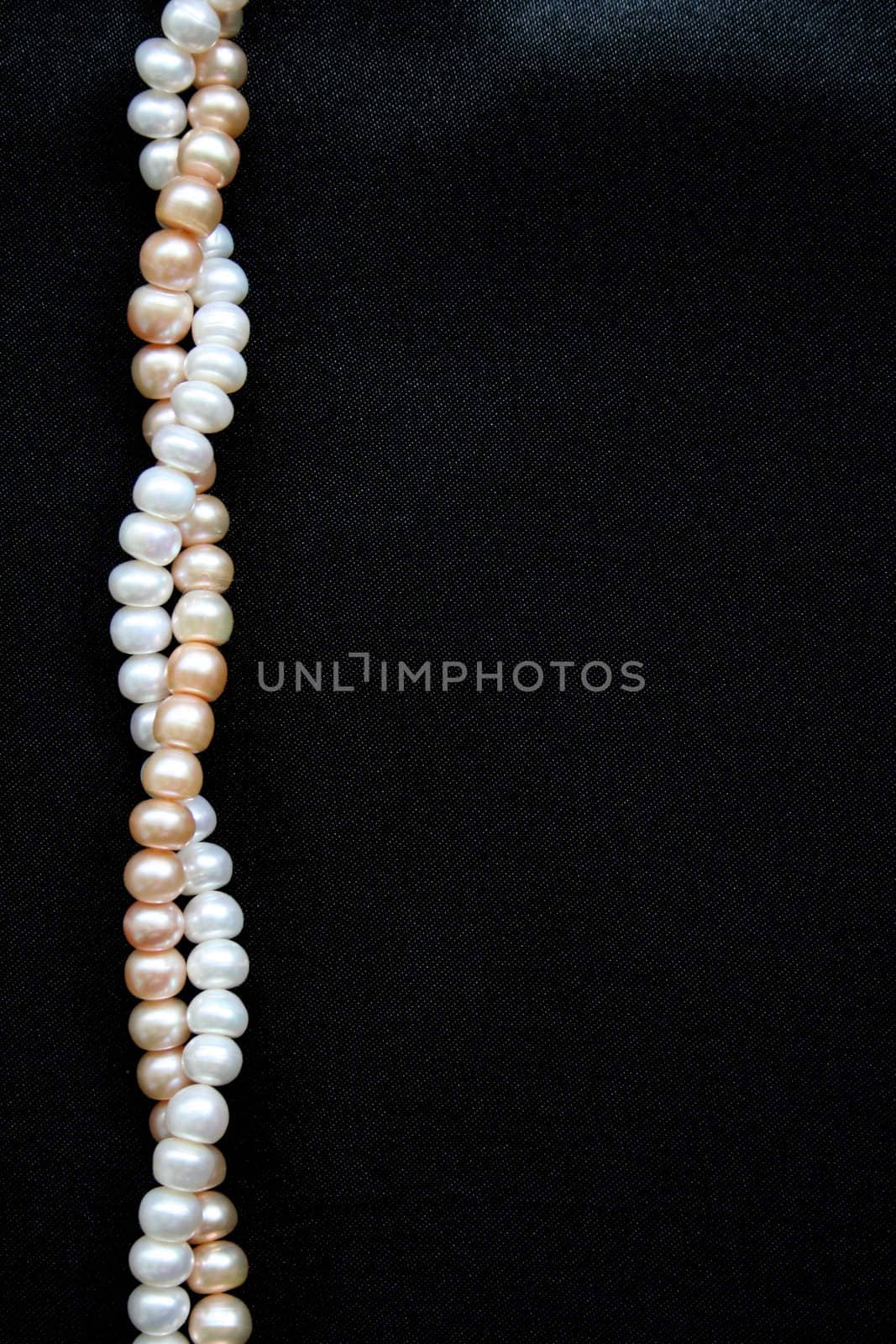 White and pink pearls on the black silk can use as background
