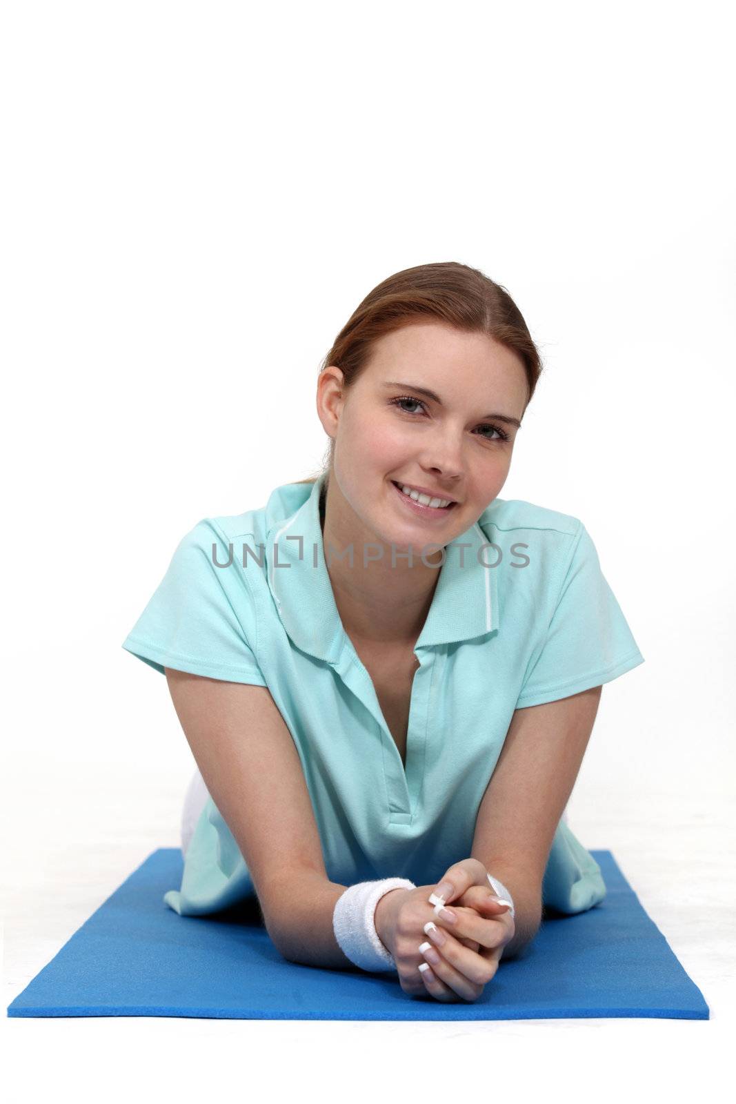 Woman lying on a yoga mat by phovoir