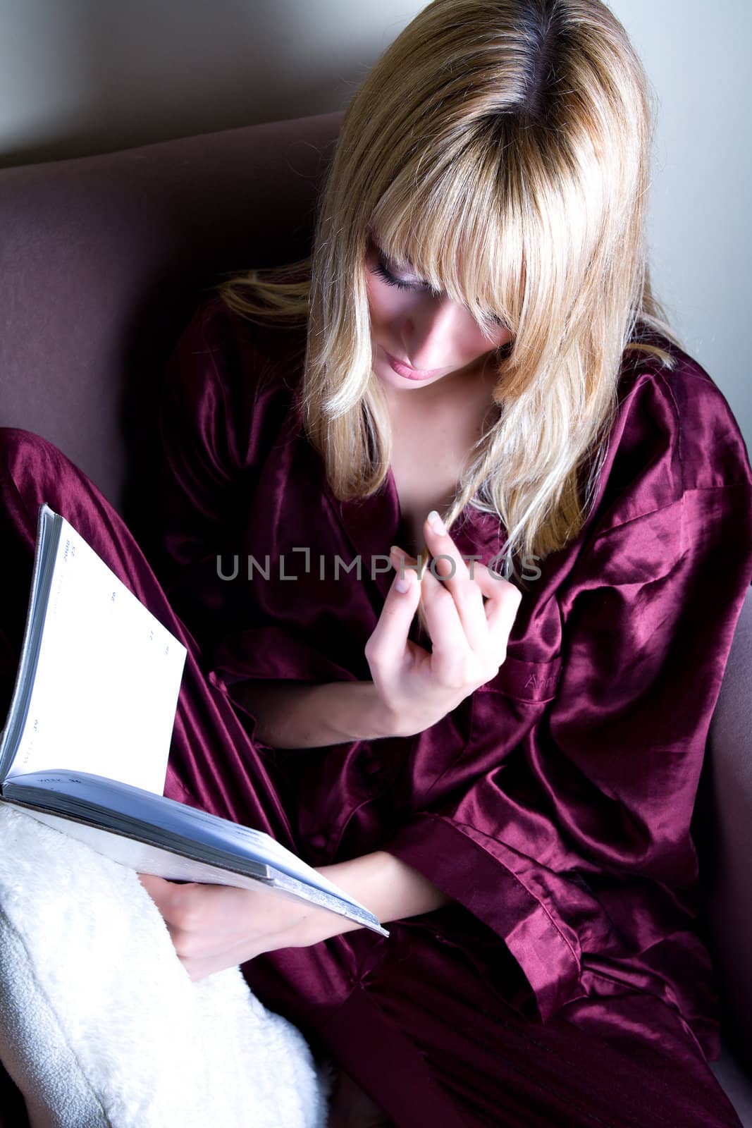 Woman is playing her hair while reading a book