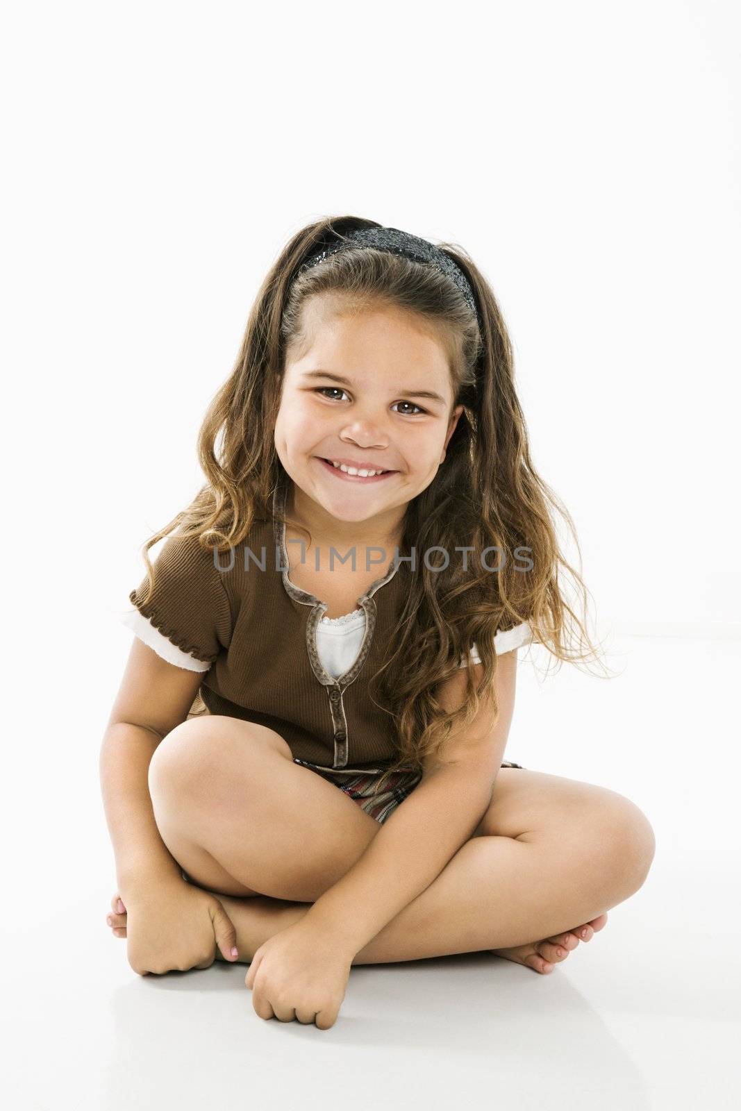 Cute little latino girl sitting looking at viewer smiling.