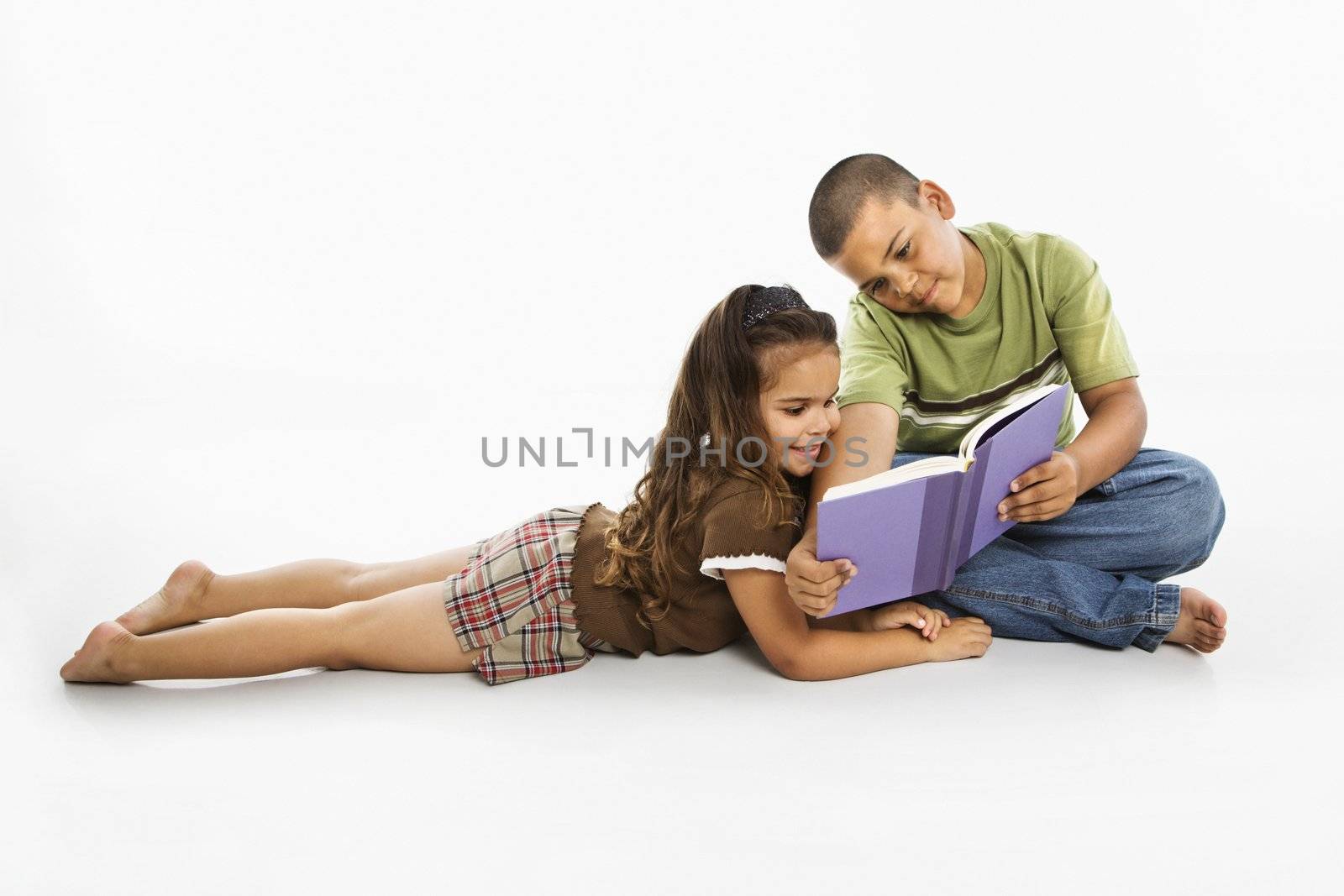 Brother and sister reading book together.