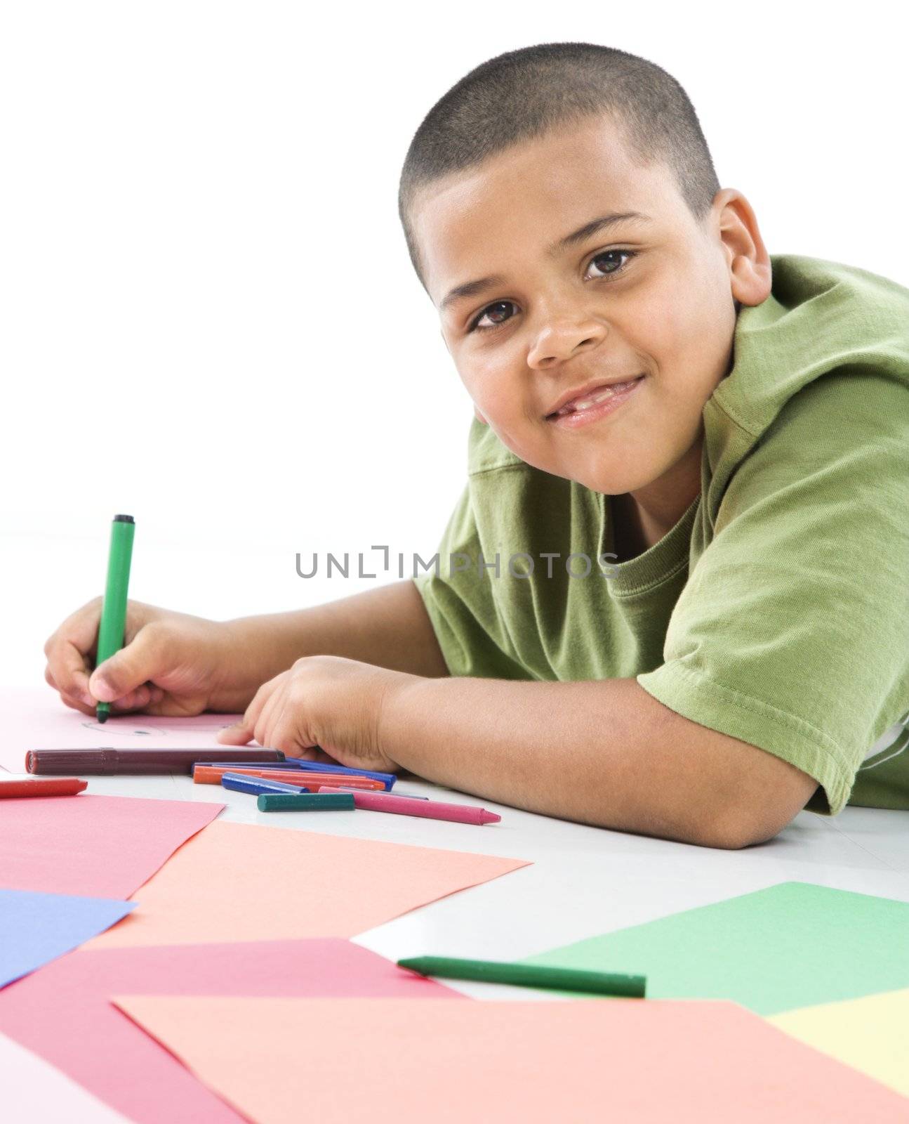 Young latino boy coloring on construction paper.