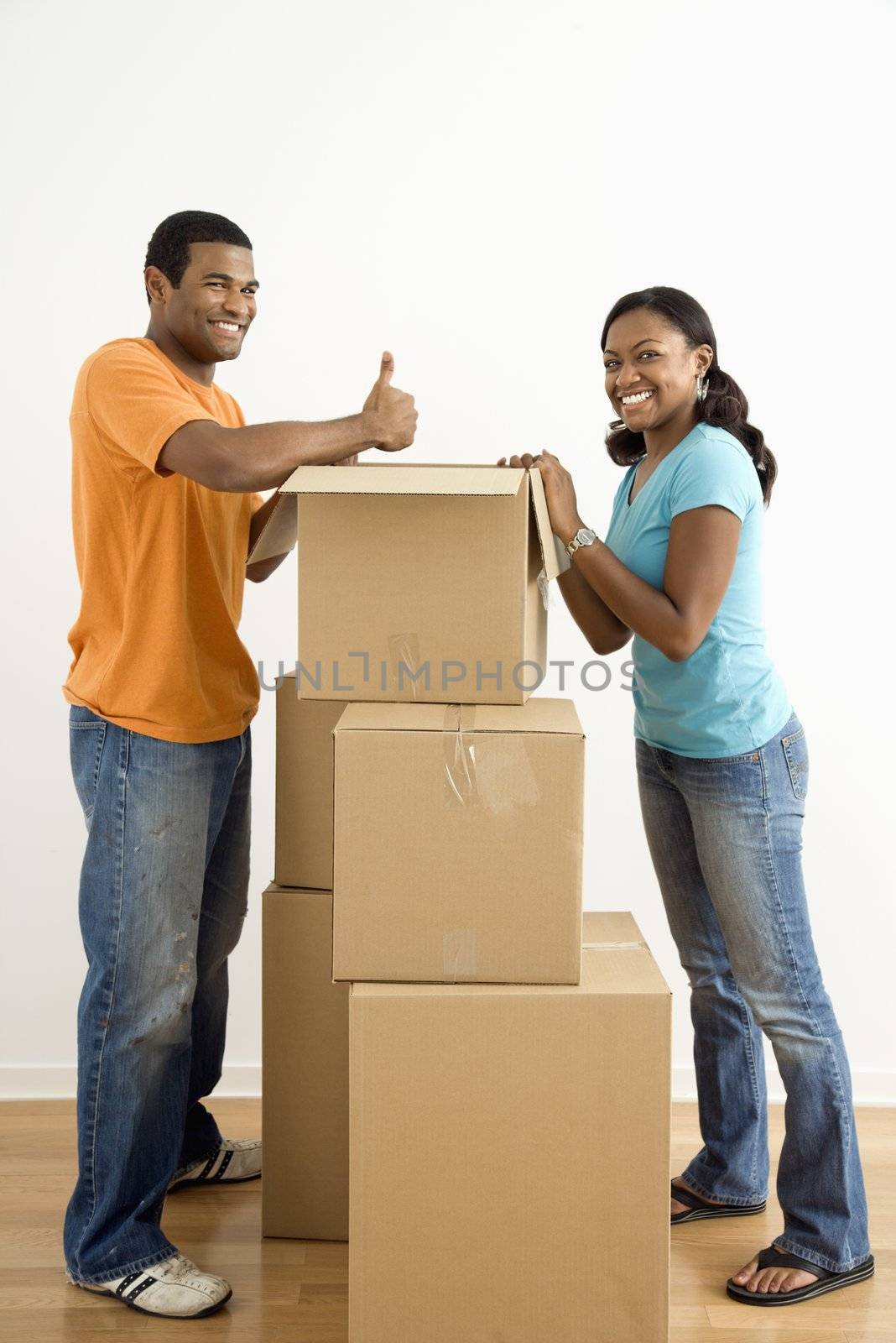 African American male and female couple packing cardboard boxes.