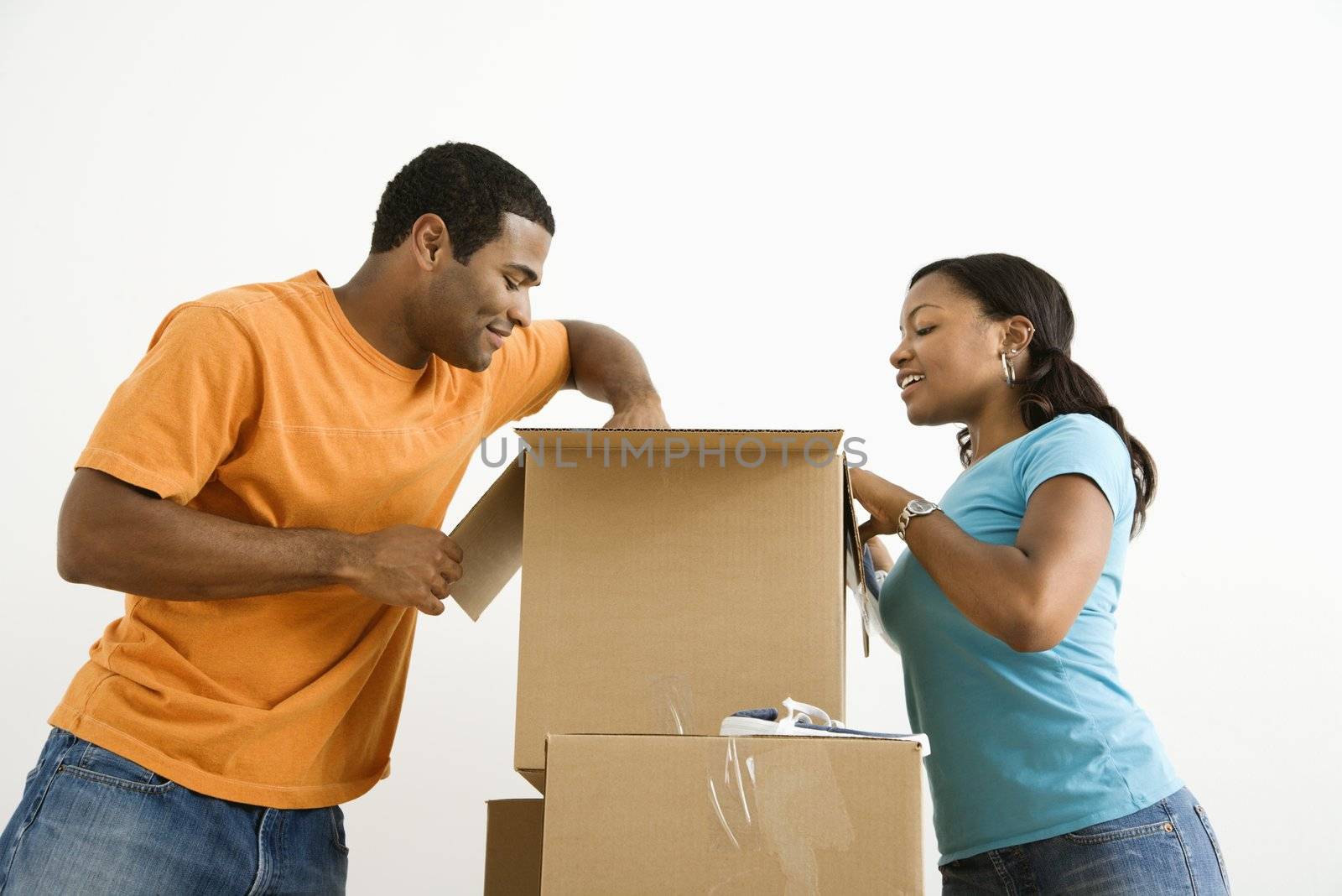 African American male and female couple packing cardboard boxes.