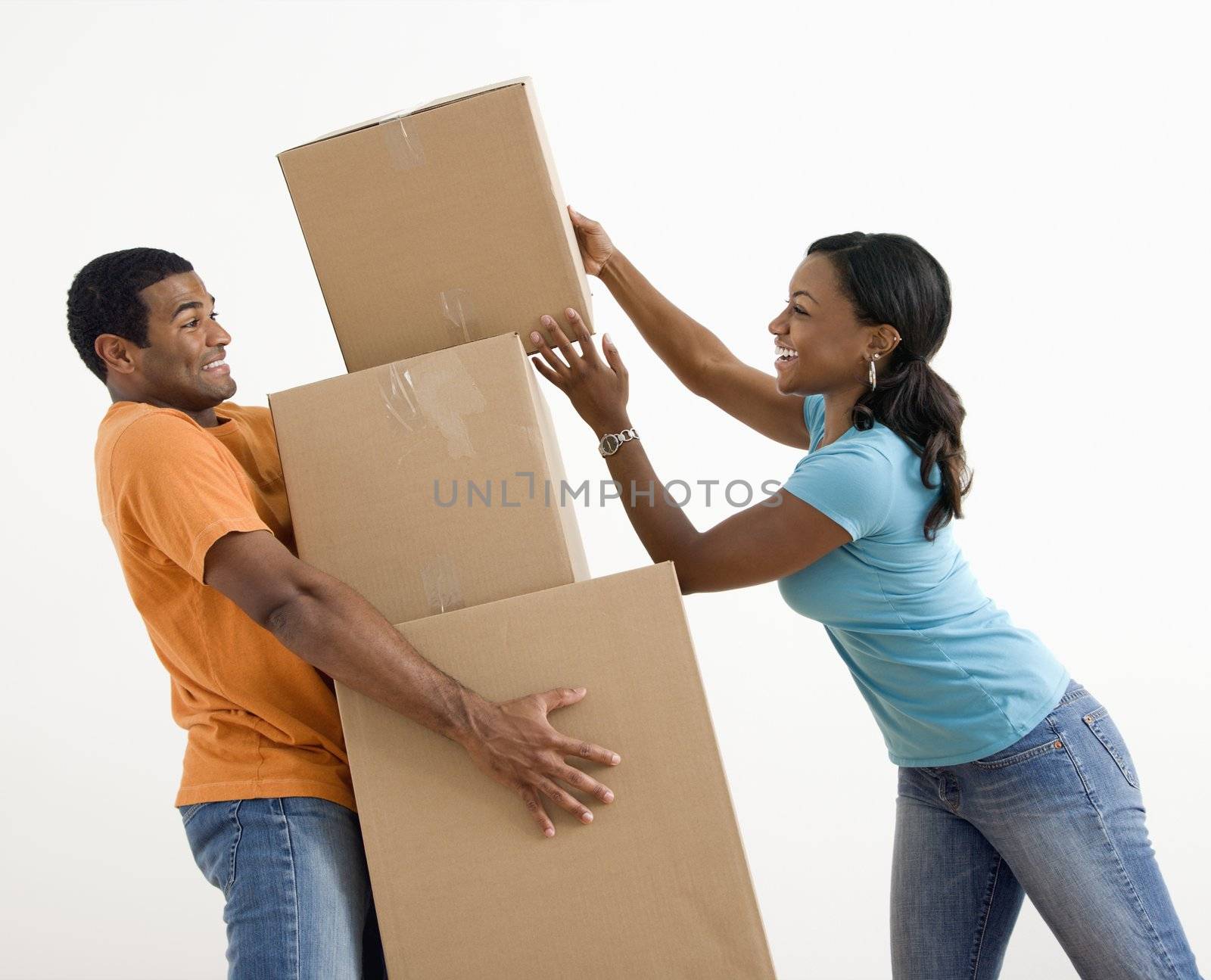 African American woman placing boxes on large stack man is holding.