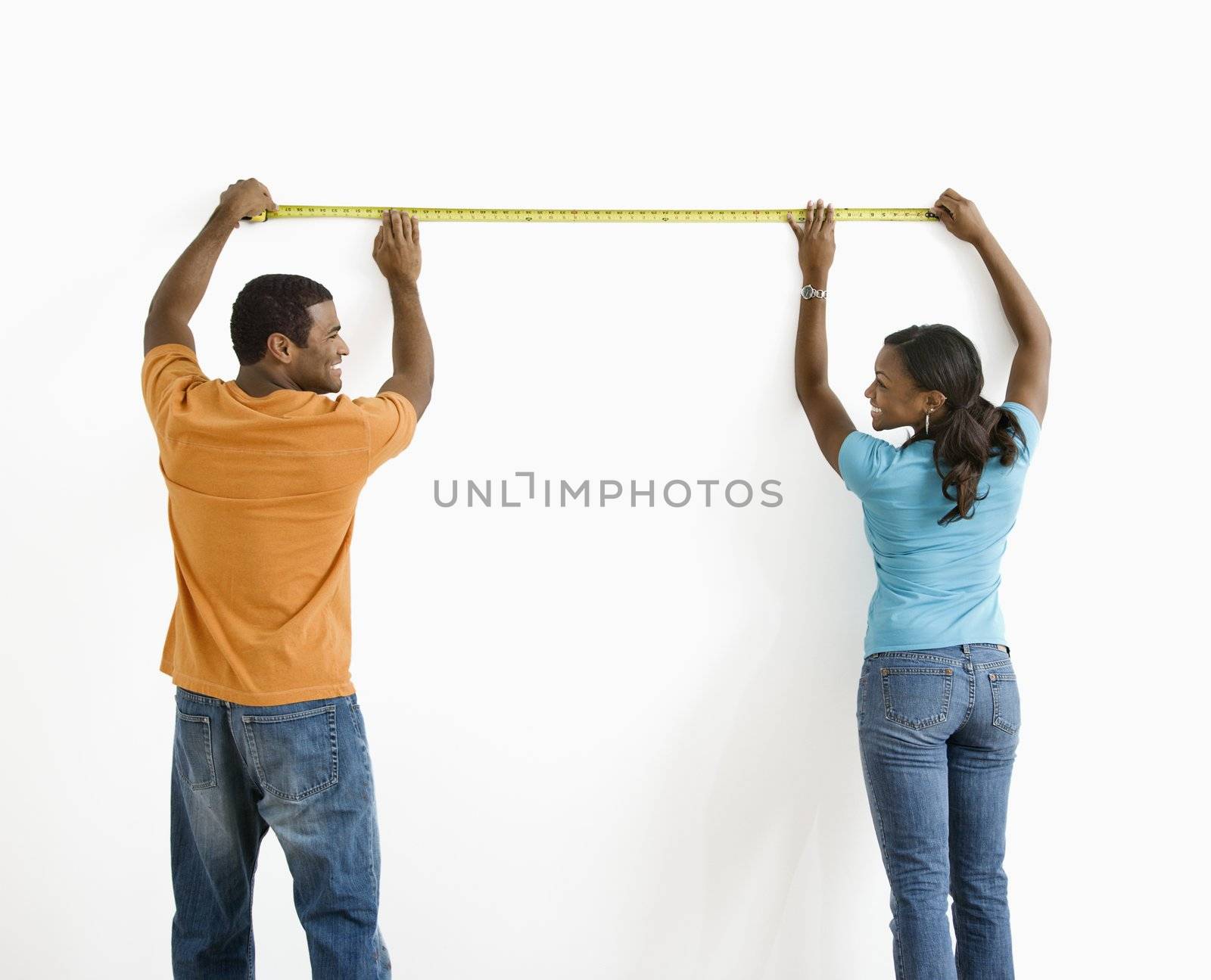 Couple measuring wall. by iofoto