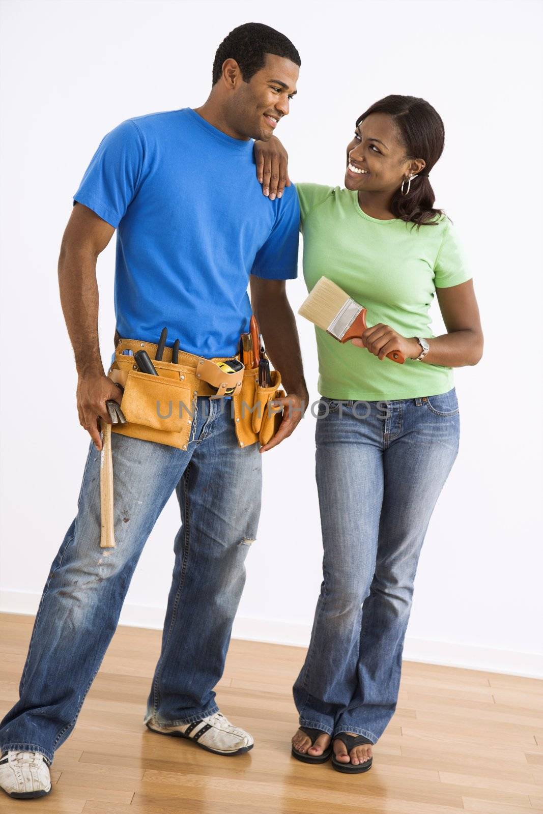 Portrait of smiling African American male and female couple with home repair tools.