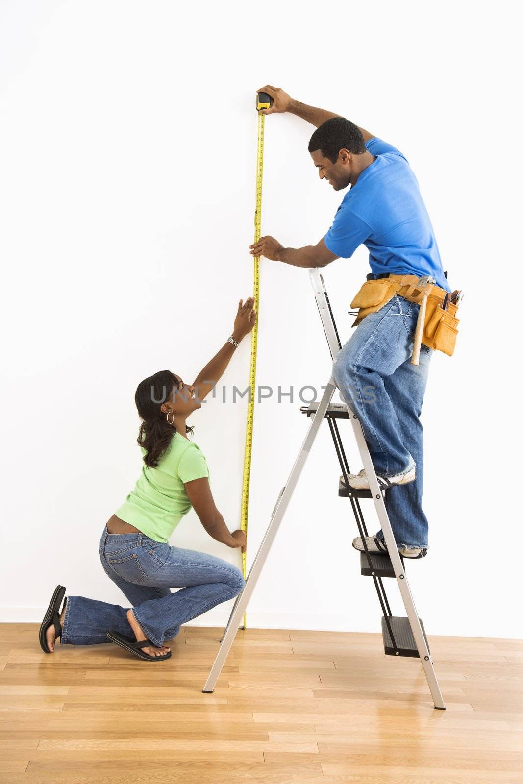 Couple measuring wall. by iofoto